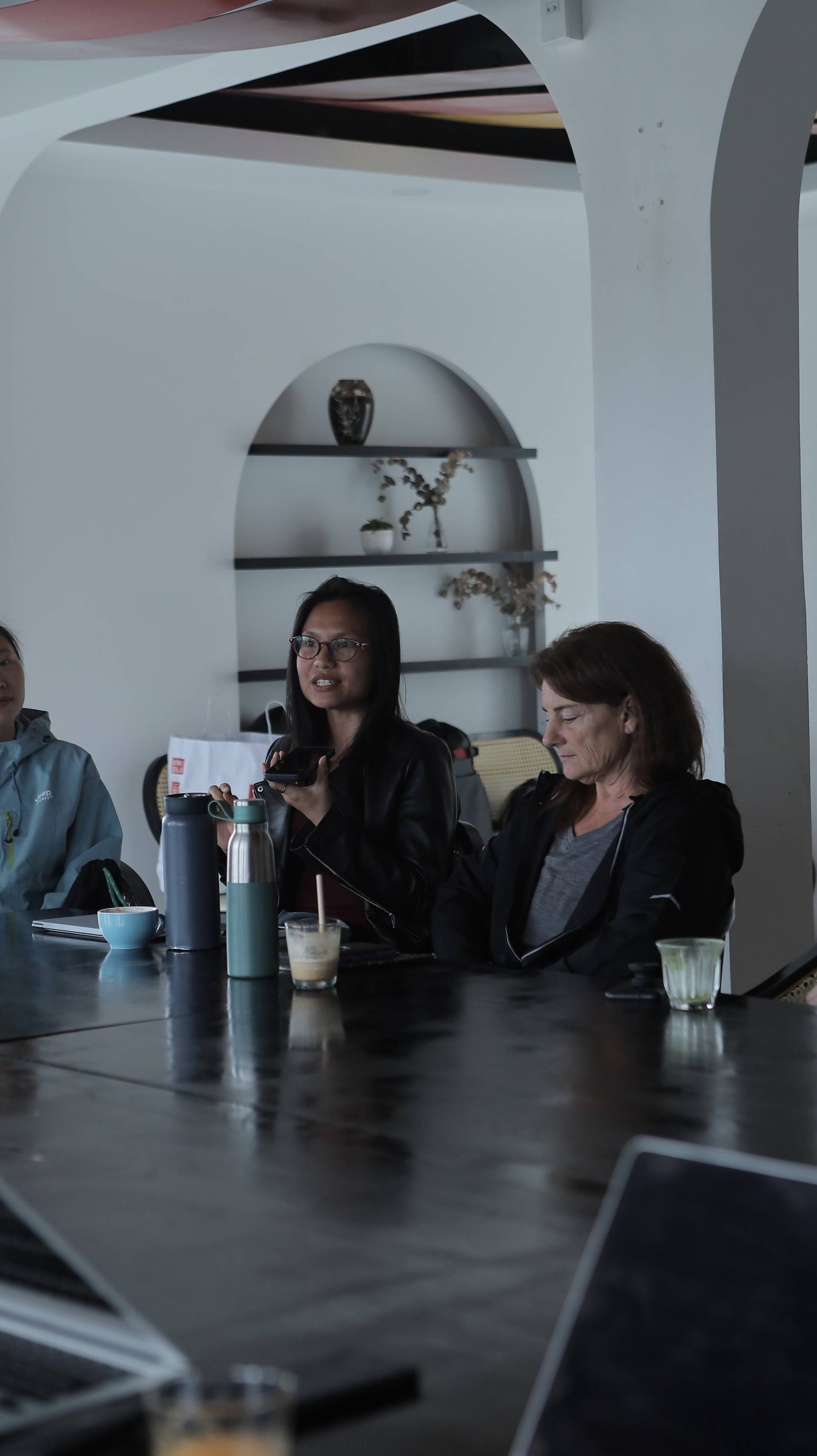 A group of individuals engaged in a casual meeting or discussion over drinks and snacks in a modern café setting in Đà Lạt, Vietnam.