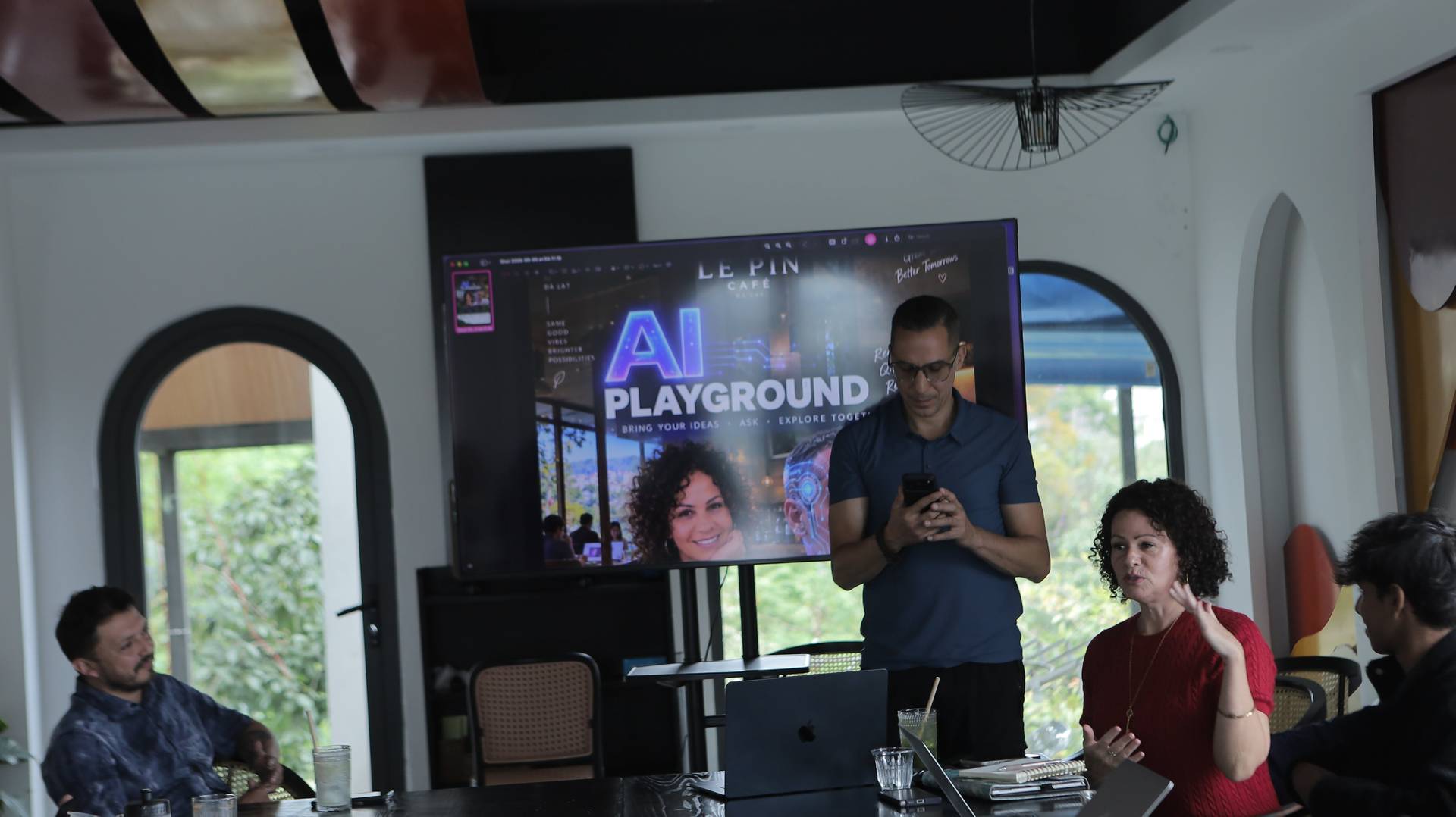 A group of people gathered in a modern café setting in Đà Lạt, Vietnam, participating in an AI-themed workshop or presentation.