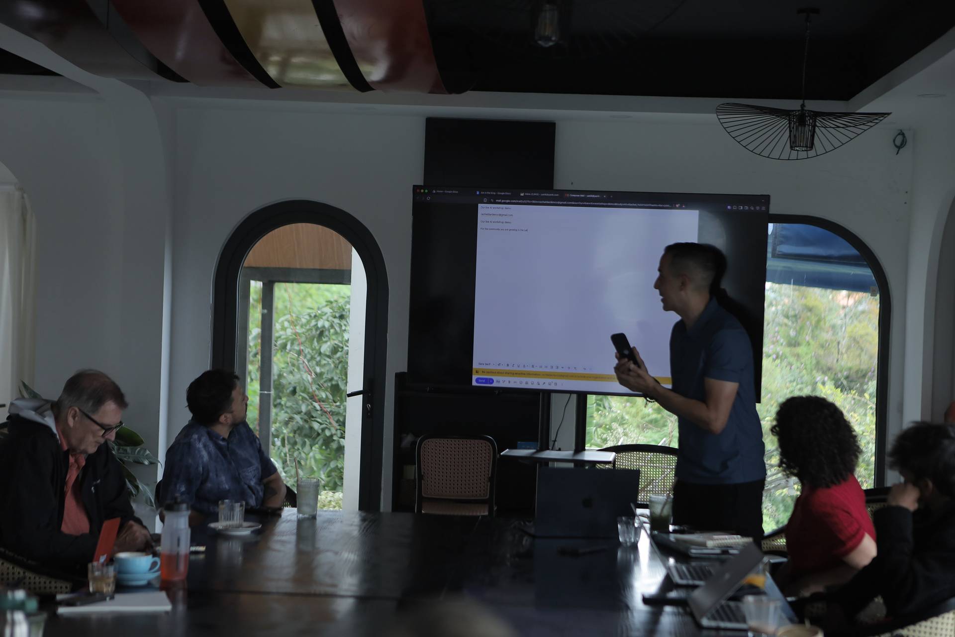 A professional presentation is being given in a modern conference room with large windows overlooking lush greenery in Đà Lạt, Vietnam.