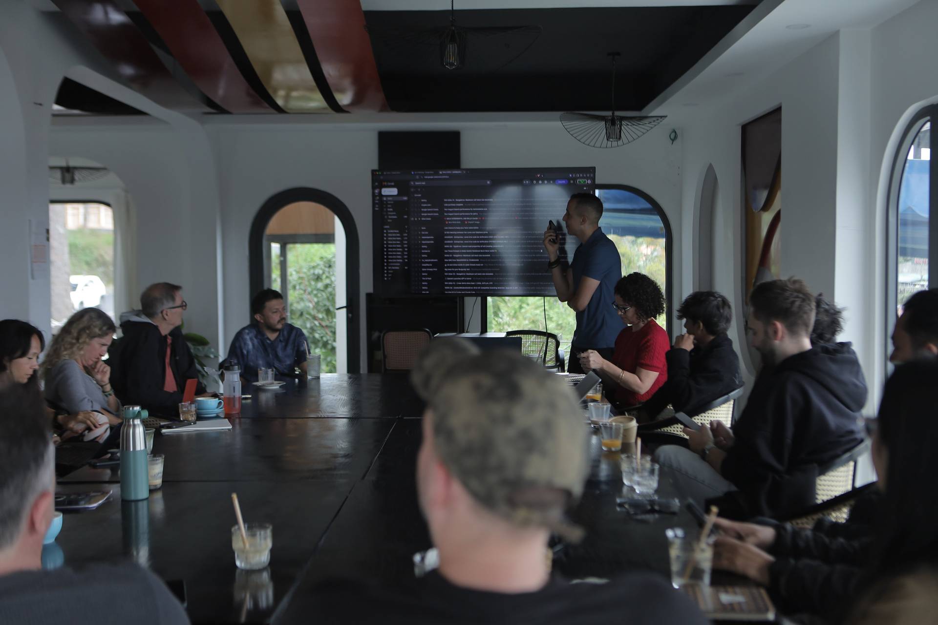 A professional meeting in a modern conference room with attendees focused on a presentation displayed on a large screen.