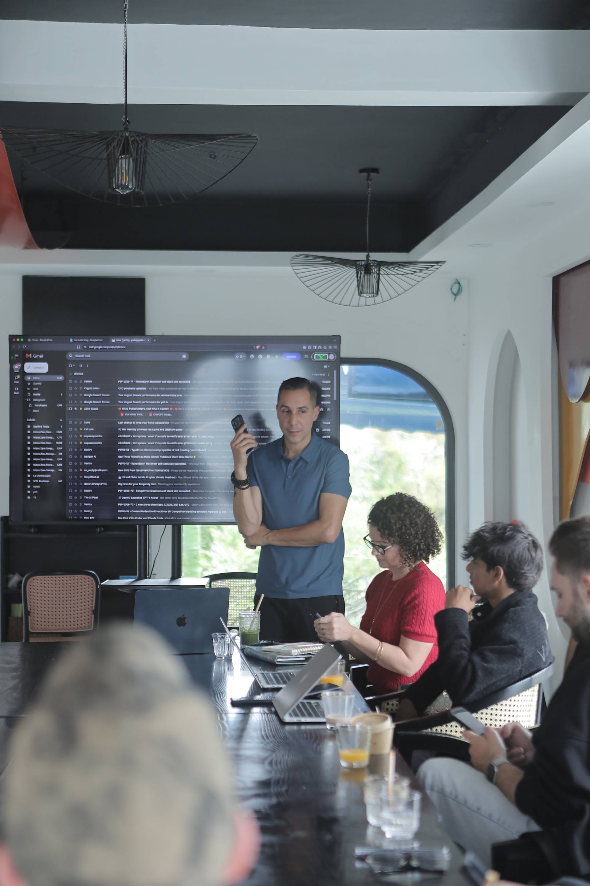 A professional meeting in a modern office space with attendees focused on a presentation displayed on a large screen.
