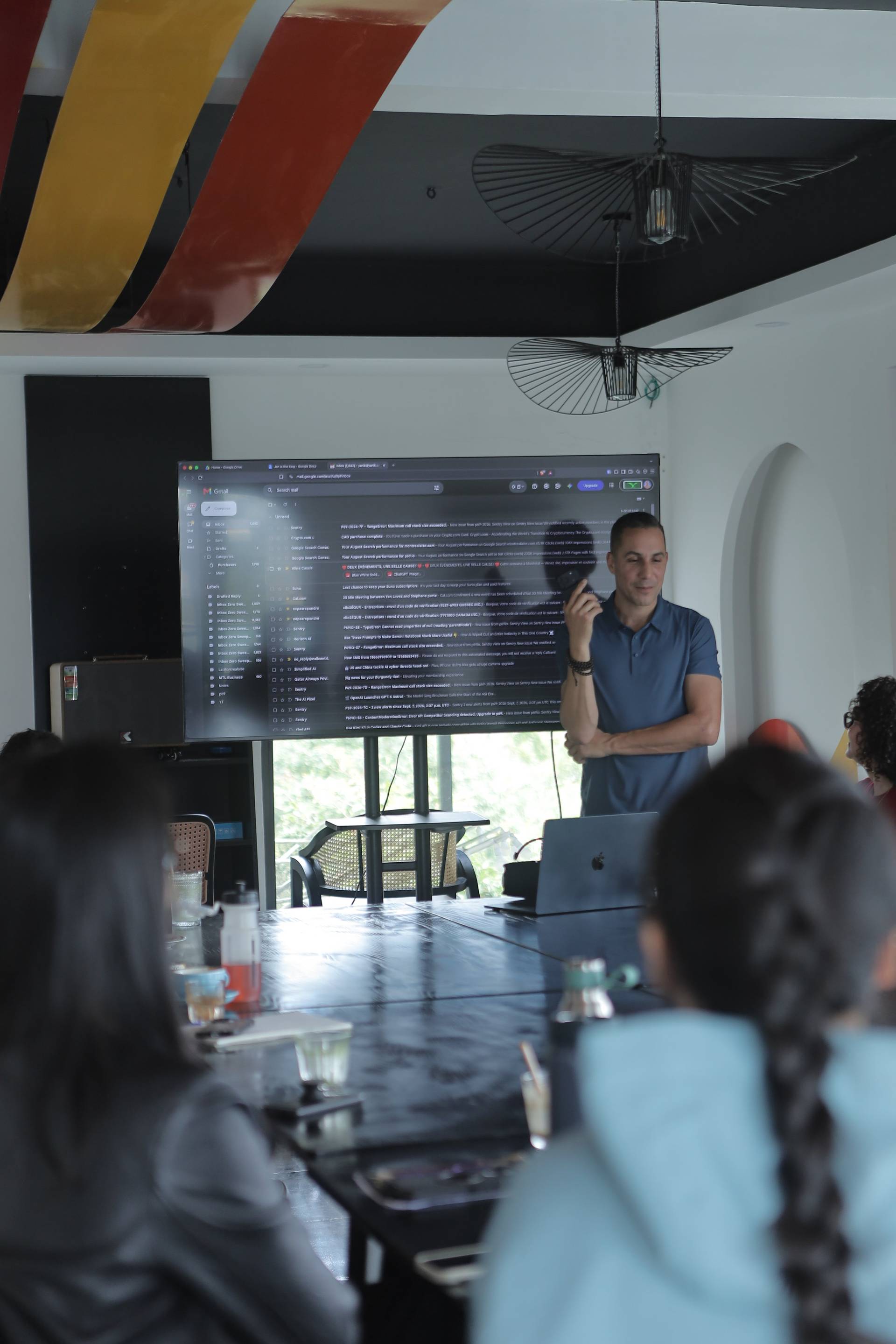 A professional meeting in a modern conference room with attendees focused on a presentation displayed on a large screen.