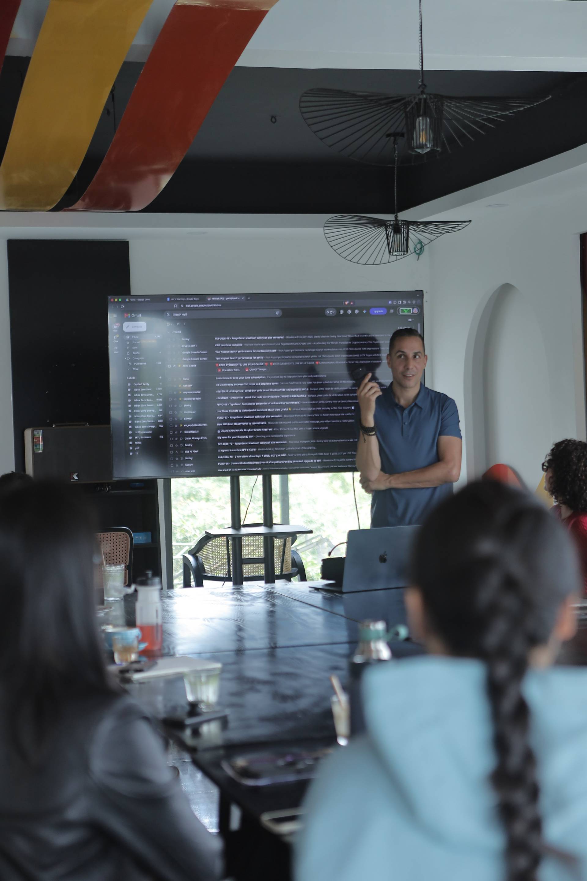 A professional meeting in a modern office space with attendees focused on a presentation displayed on a large screen.