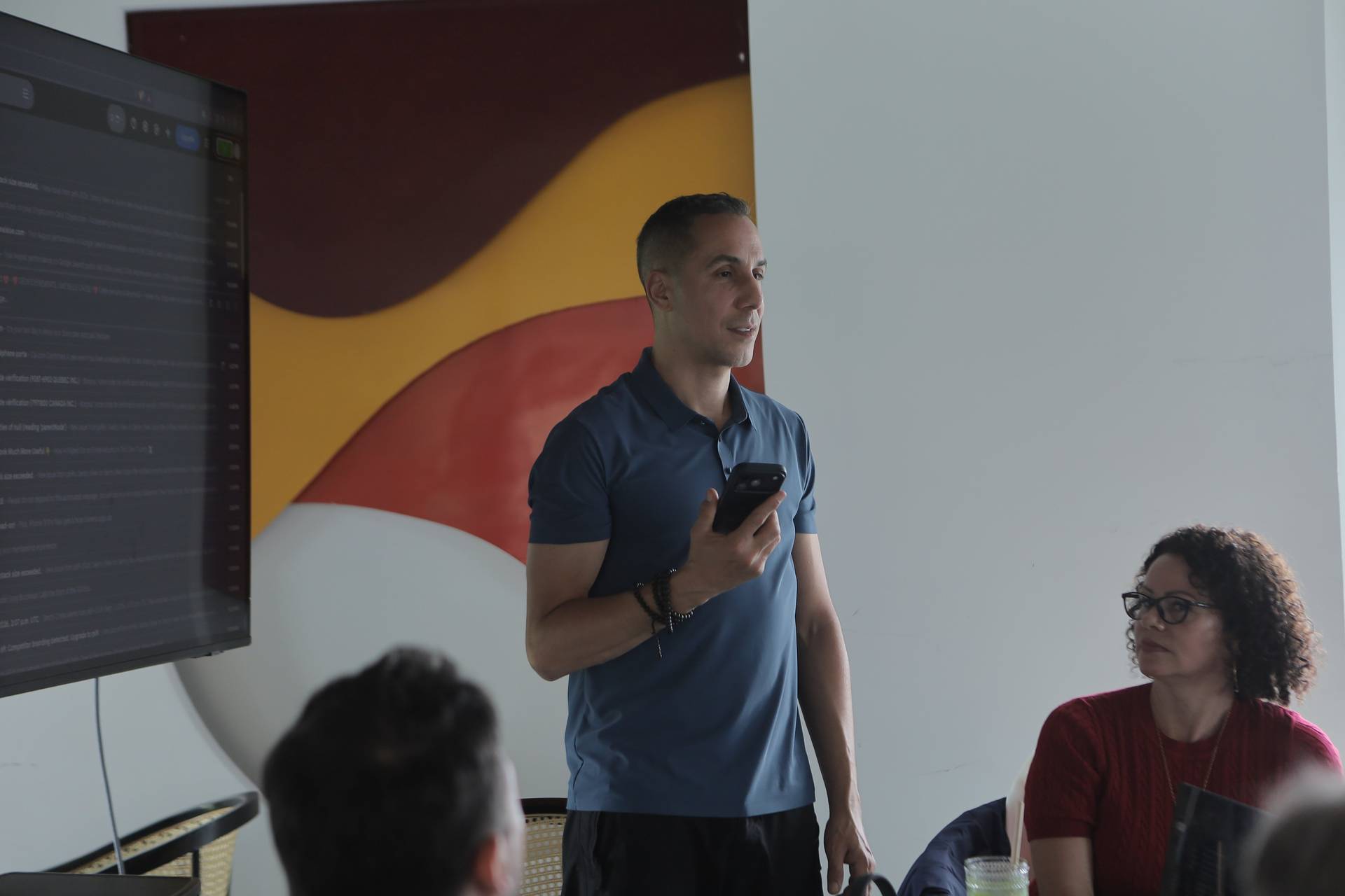 A man is presenting to a small audience in Đà Lạt, Vietnam, with a colorful abstract mural as the backdrop.