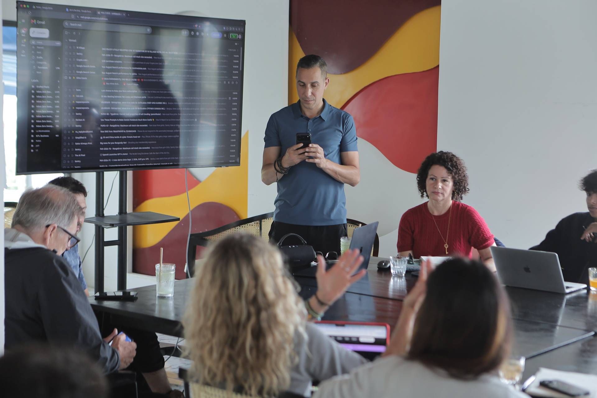 A professional meeting in a modern office space with attendees engaged in discussion around a conference table.