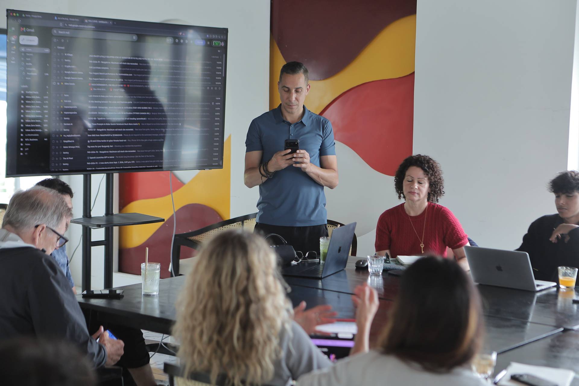 A professional meeting in a modern office setting with participants engaged in discussion around a conference table.