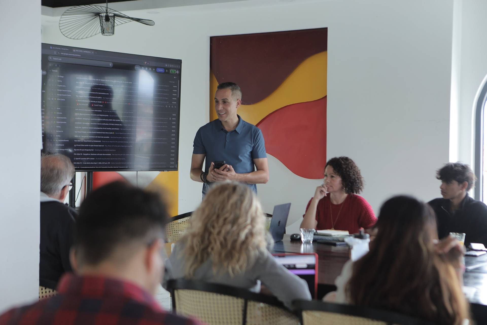 A professional meeting in a modern office space with attendees focused on a presentation displayed on a large screen.