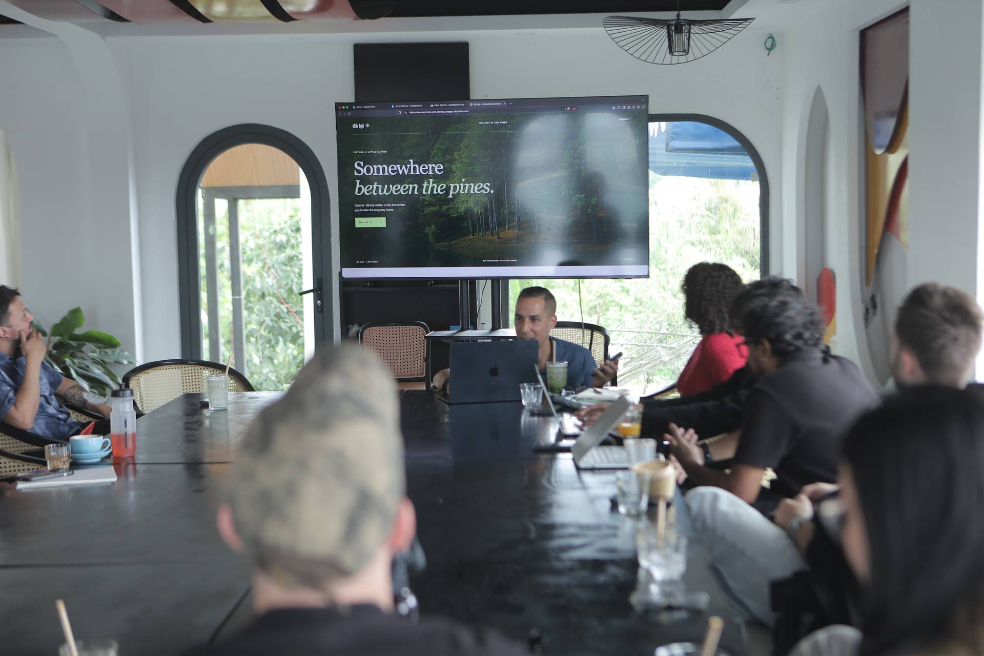 A group of people is gathered around a conference table in Đà Lạt, Vietnam, discussing and presenting ideas related to the city's natural beauty and lifestyle.