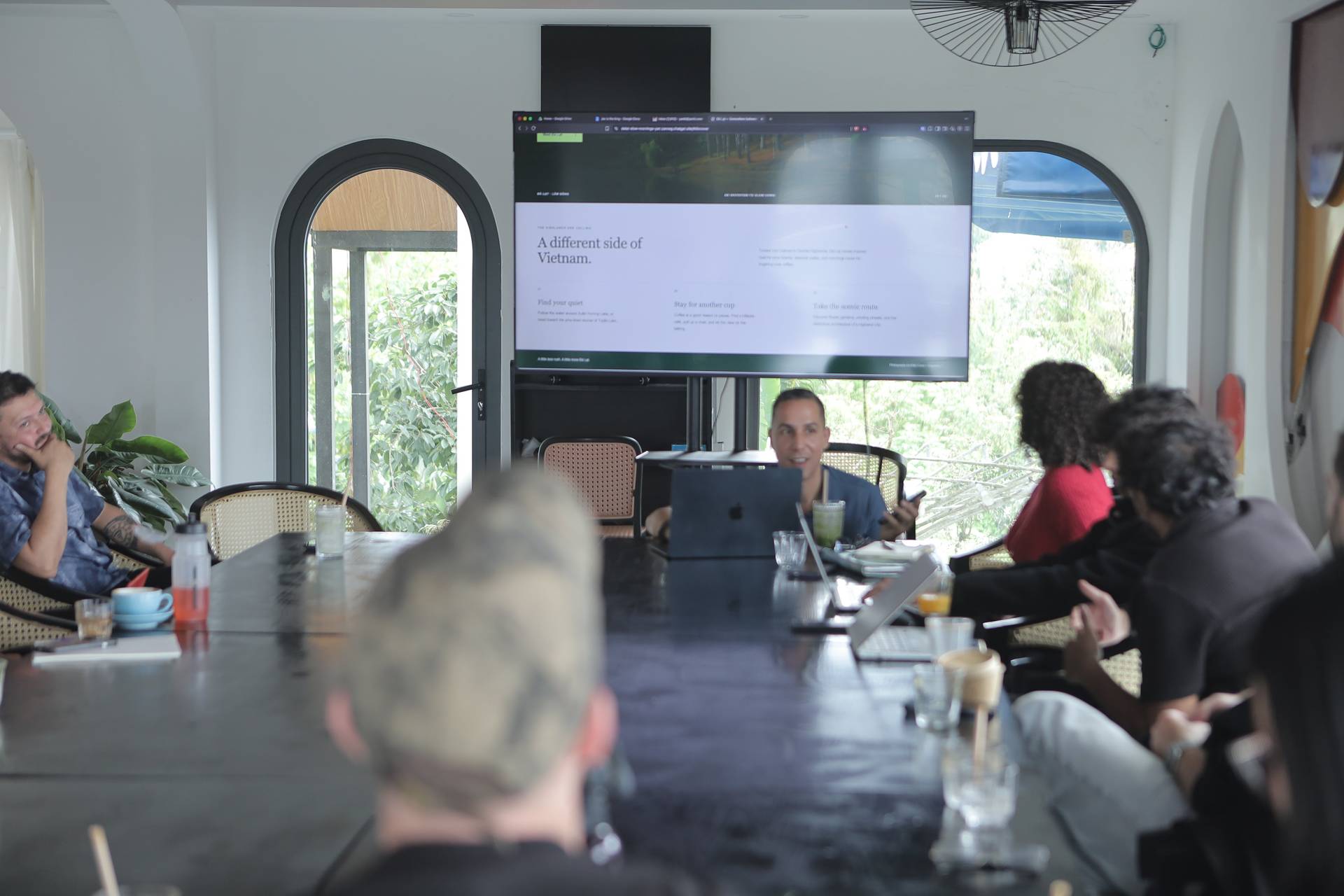 A group of people is gathered around a conference table in Đà Lạt, Vietnam, discussing and presenting ideas related to exploring different sides of the region.