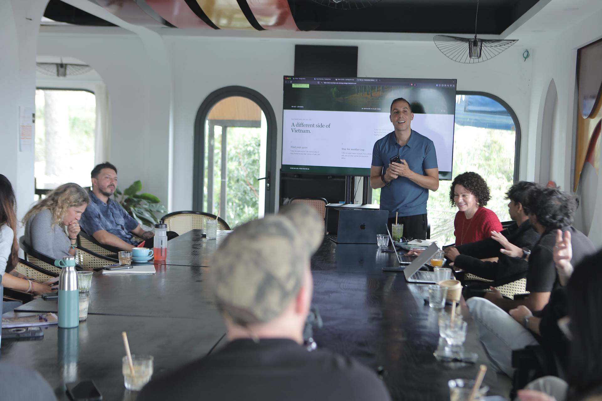 A group of people is gathered in a modern conference room in Đà Lạt, Vietnam, engaging in a presentation about exploring different sides of the country.