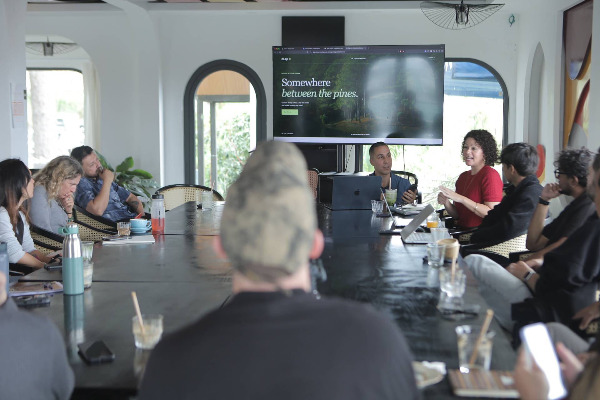 A group of professionals is engaged in a collaborative meeting in Đà Lạt, Vietnam, discussing a scenic advertisement featuring pine forests.
