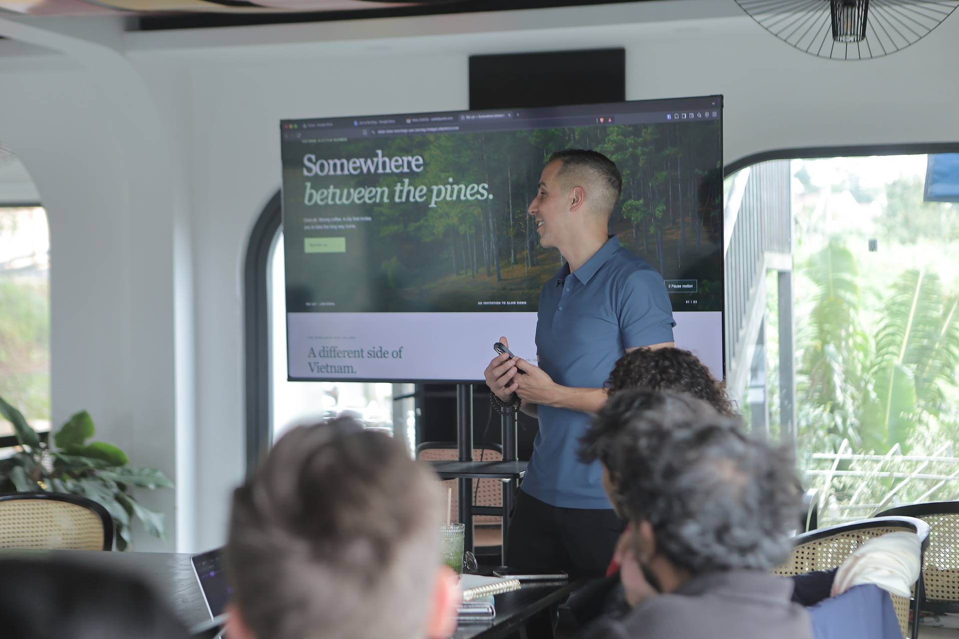 A presenter shares insights about a pine forest in Đà Lạt during a seminar, with attendees seated and engaged.