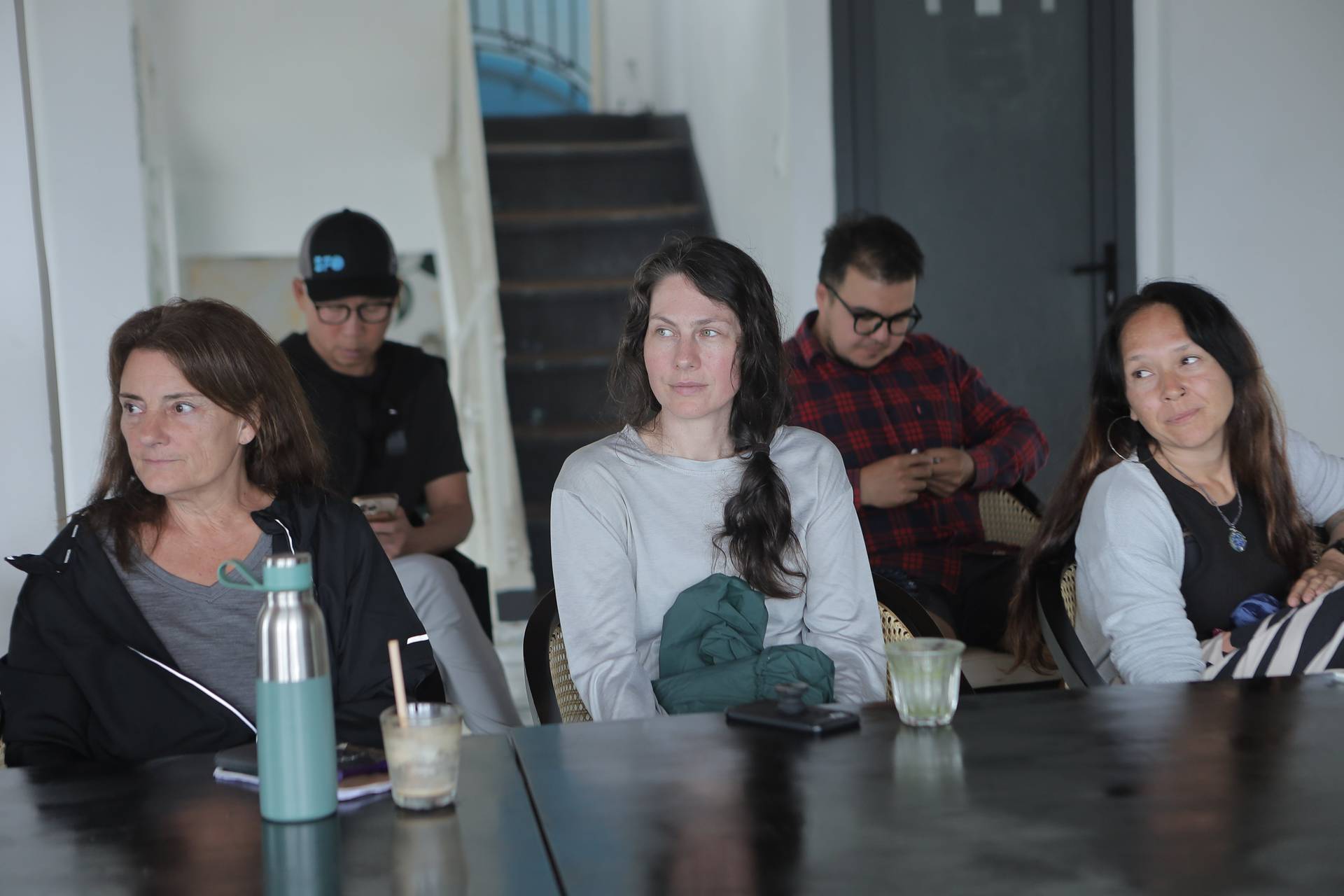 A group of individuals is seated around a table in what appears to be a casual setting within Đà Lạt, Vietnam, engaging in conversation or listening attentively during an event.
