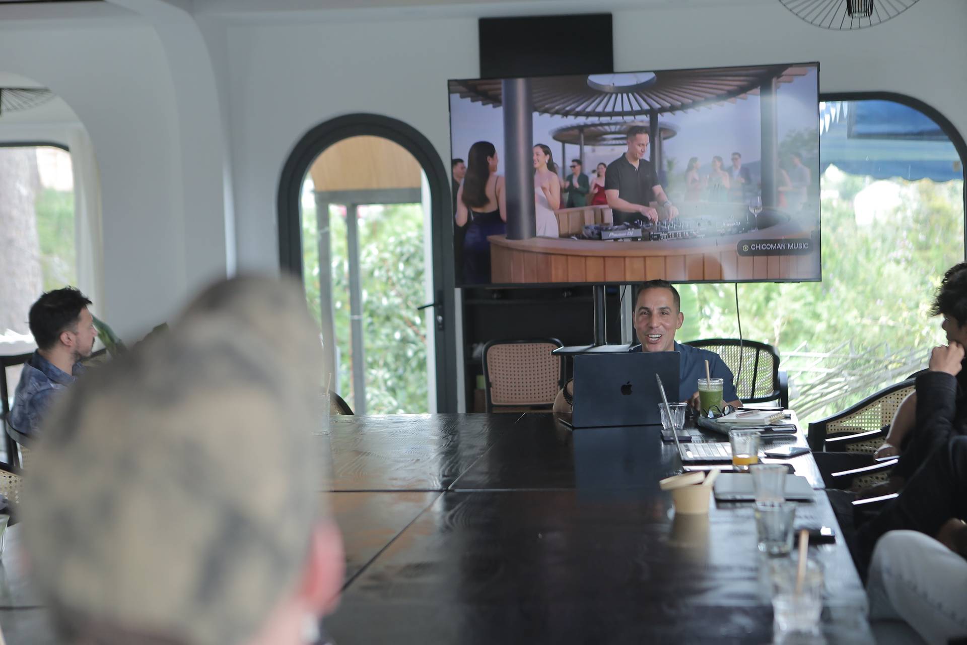 A group of friends enjoys a virtual DJ performance in a modern Vietnamese setting with scenic views.