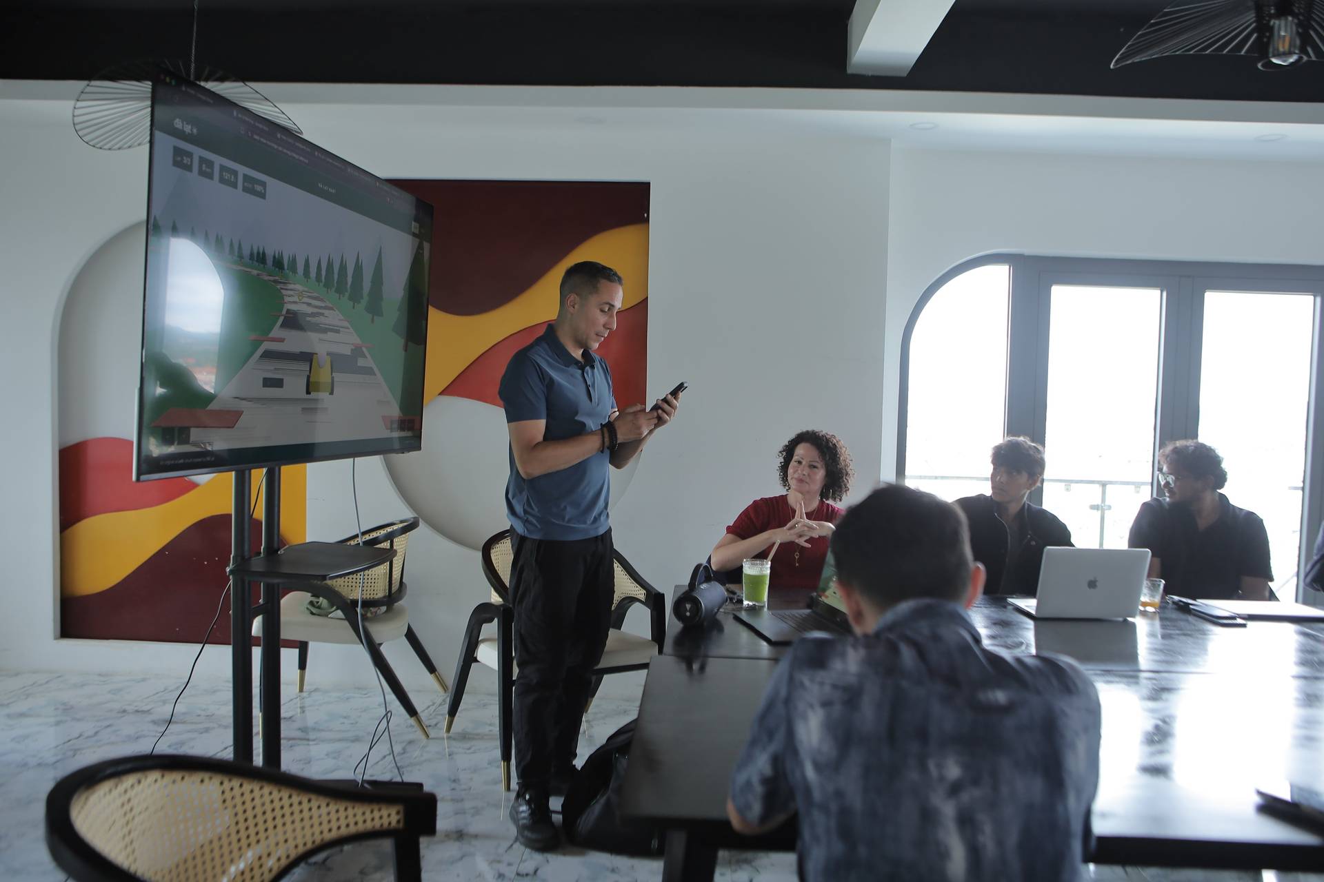 A professional meeting in Đà Lạt, Vietnam, featuring a presentation with a digital display showing a scenic route, while participants engage attentively at a conference table.