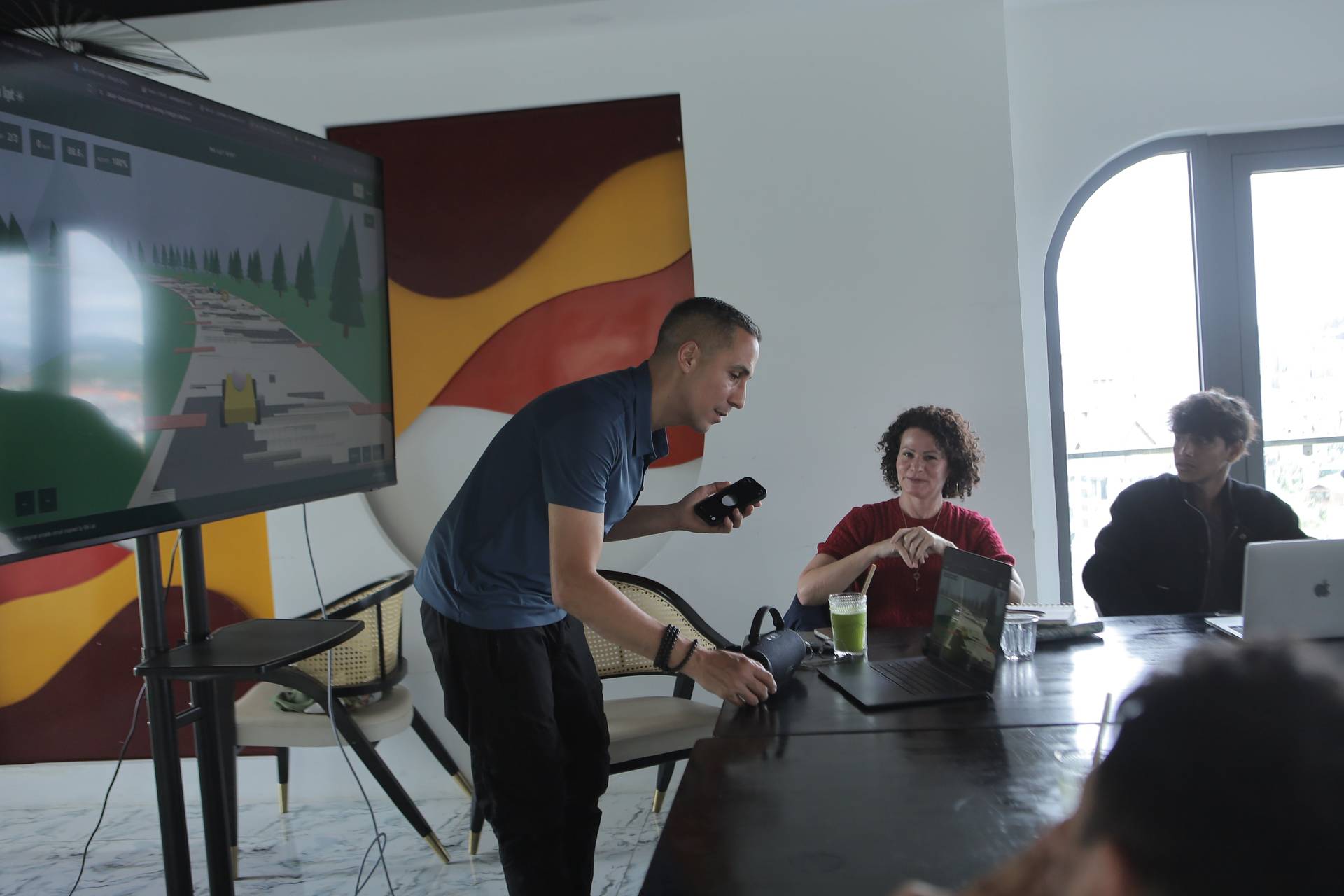 A group of professionals collaborates in a modern office space with vibrant artwork and large windows overlooking Đà Lạt's scenic landscapes.