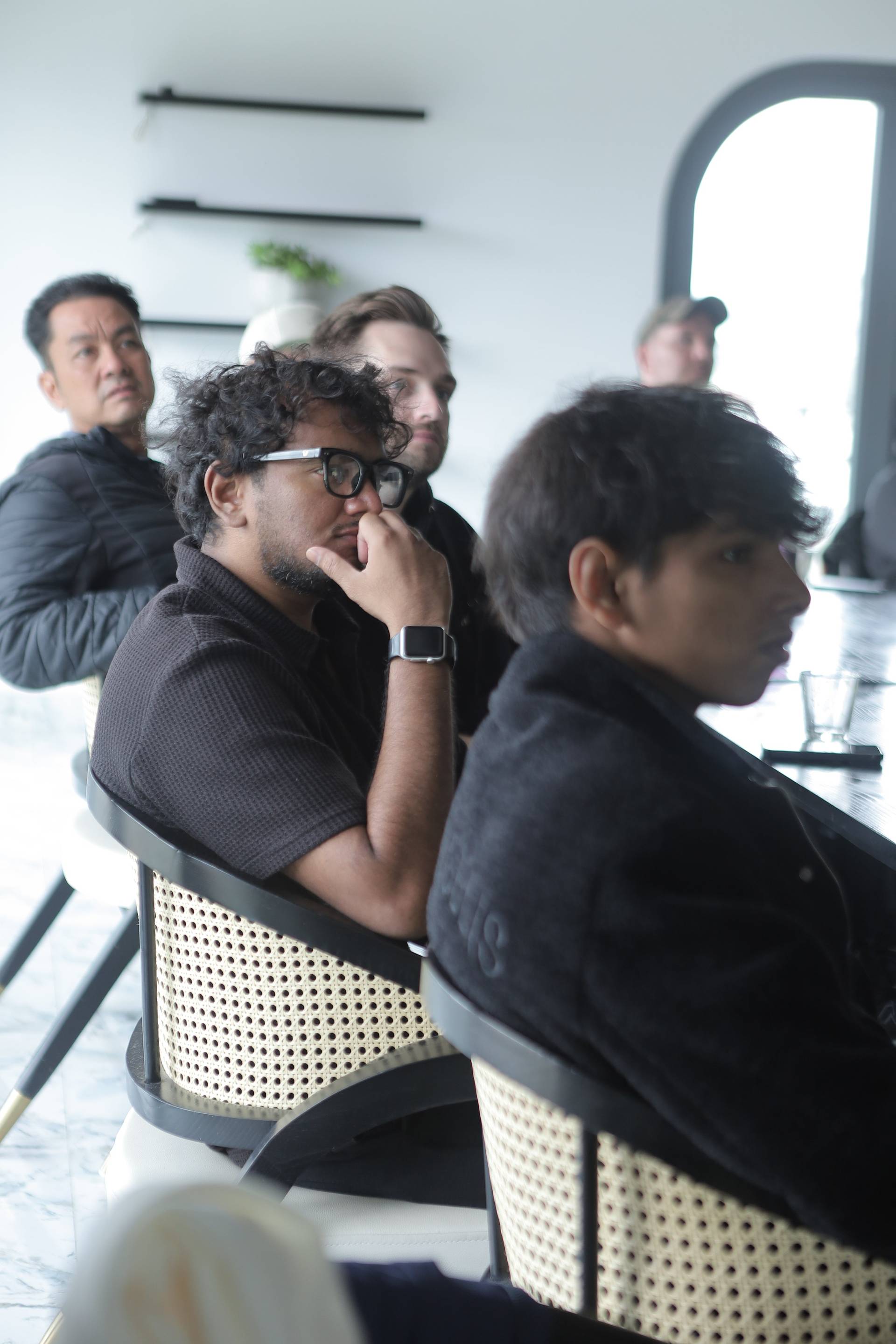 A group of individuals attentively listening in a modern café setting in Đà Lạt, Vietnam.