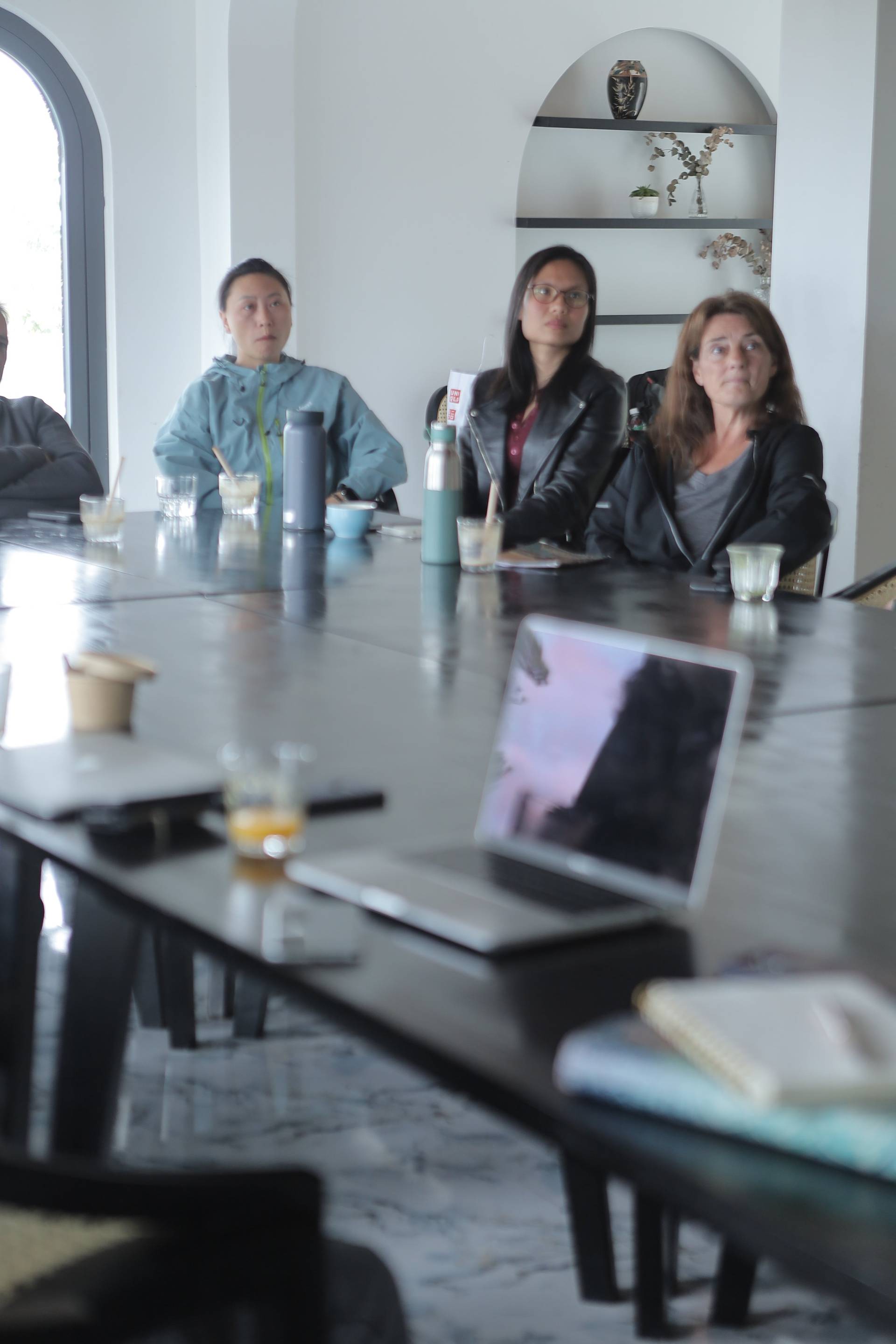 A group of individuals engaged in a meeting or discussion around a modern table with a laptop and refreshments, set against a serene backdrop typical of Đà Lạt's natural beauty.