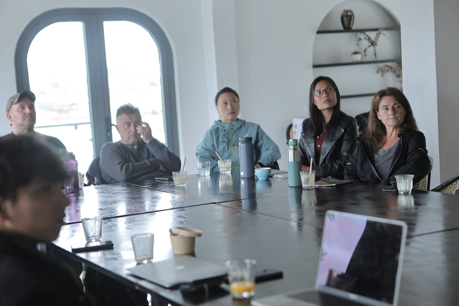 A group of individuals is gathered around a large table in a modern setting, engaged in what appears to be a professional or collaborative meeting in Đà Lạt, Vietnam.