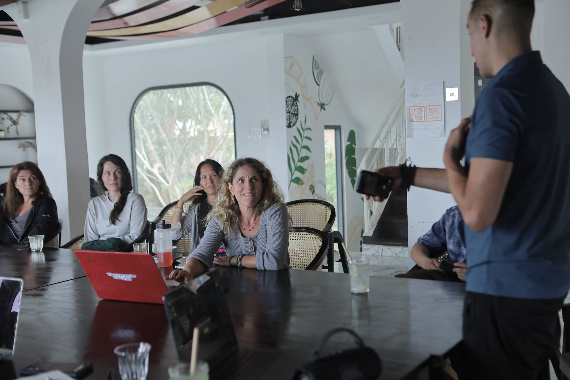 A group of people is engaged in a presentation or discussion within a modern café setting in Đà Lạt, Vietnam.
