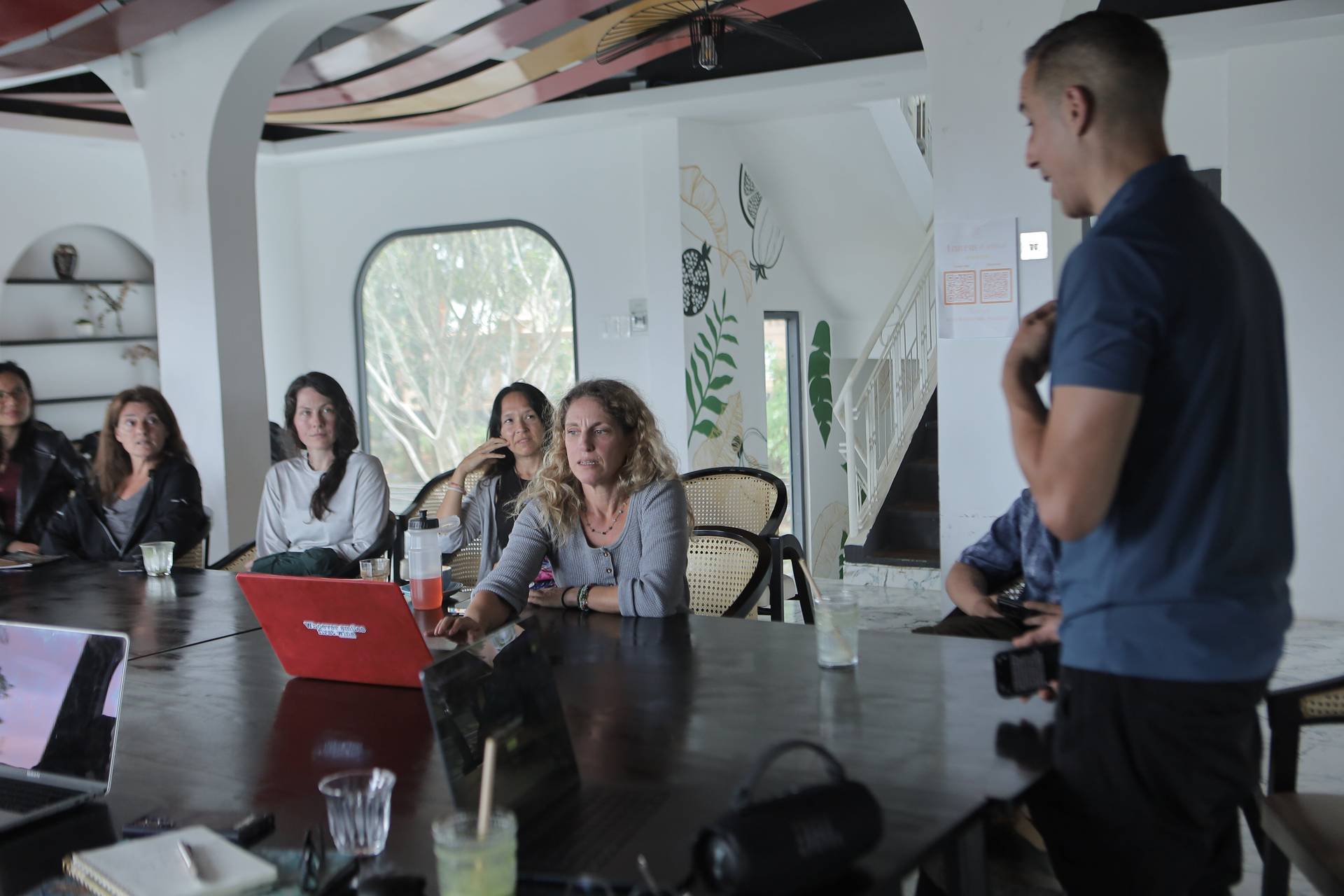 A group of individuals is engaged in a presentation or discussion within a modern, well-lit café setting in Đà Lạt, Vietnam.