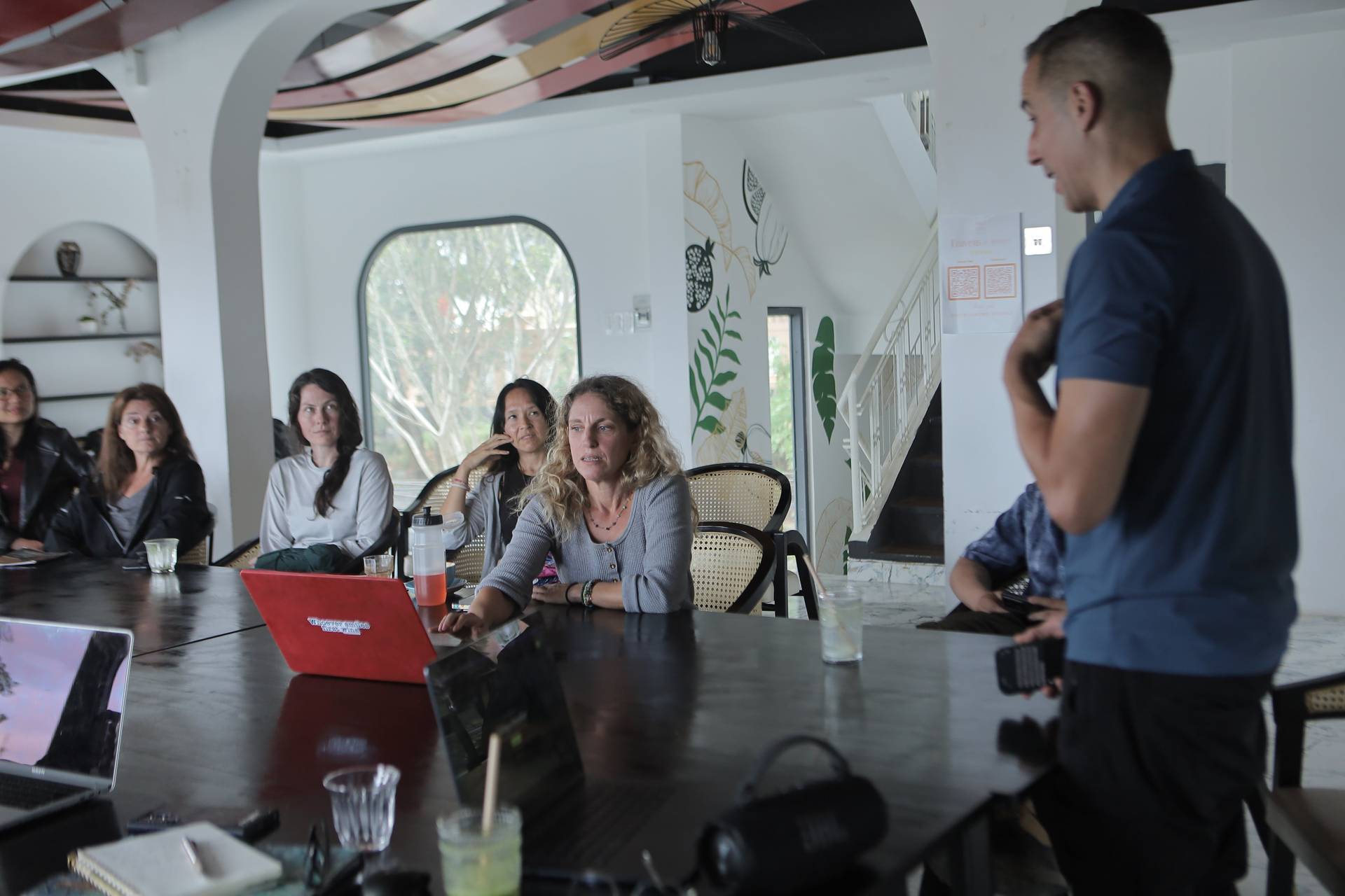A group of people is engaged in a discussion or presentation within a modern café setting in Đà Lạt, Vietnam.