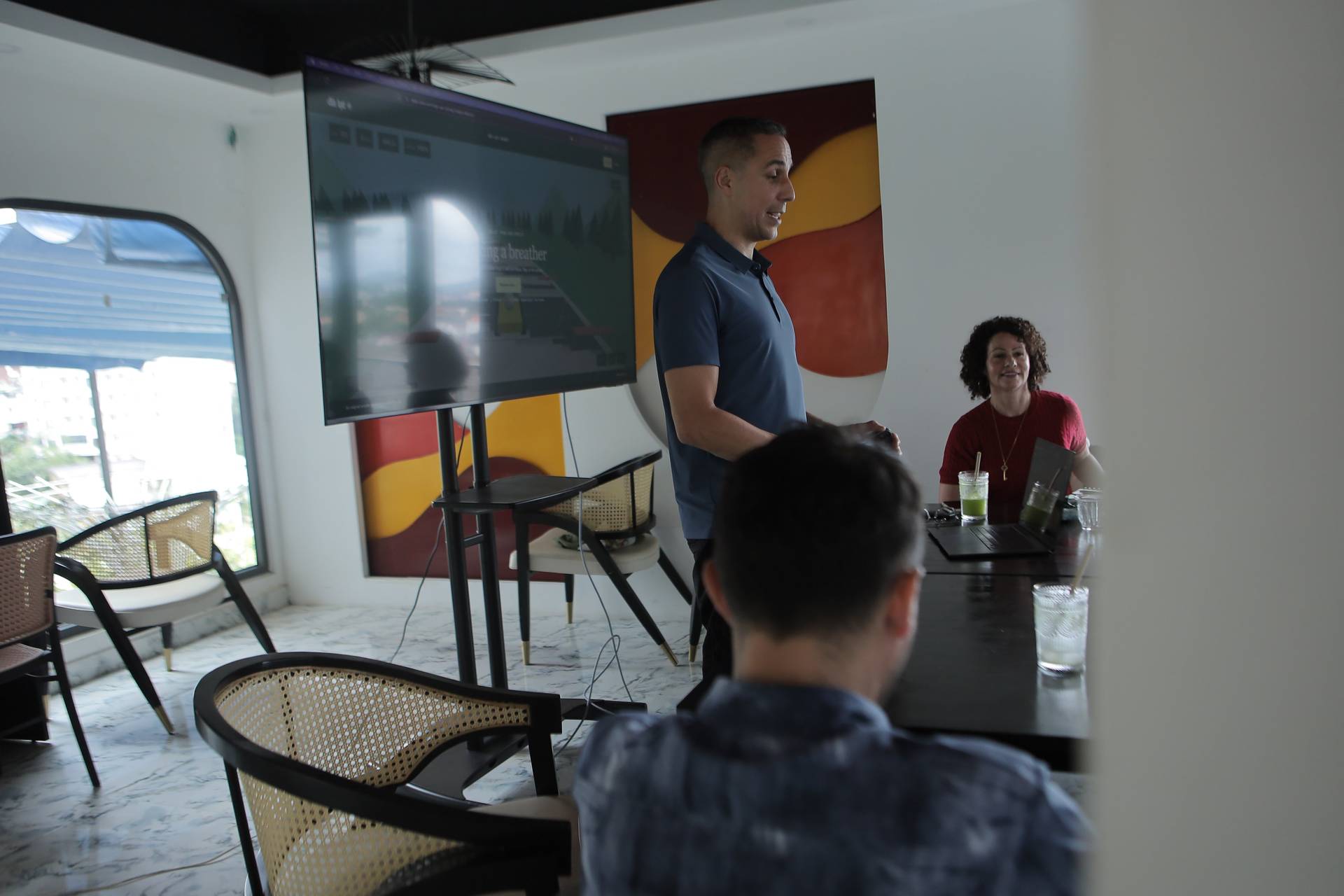 A professional presentation is taking place in a modern office space with large windows overlooking Đà Lạt's scenic landscape.
