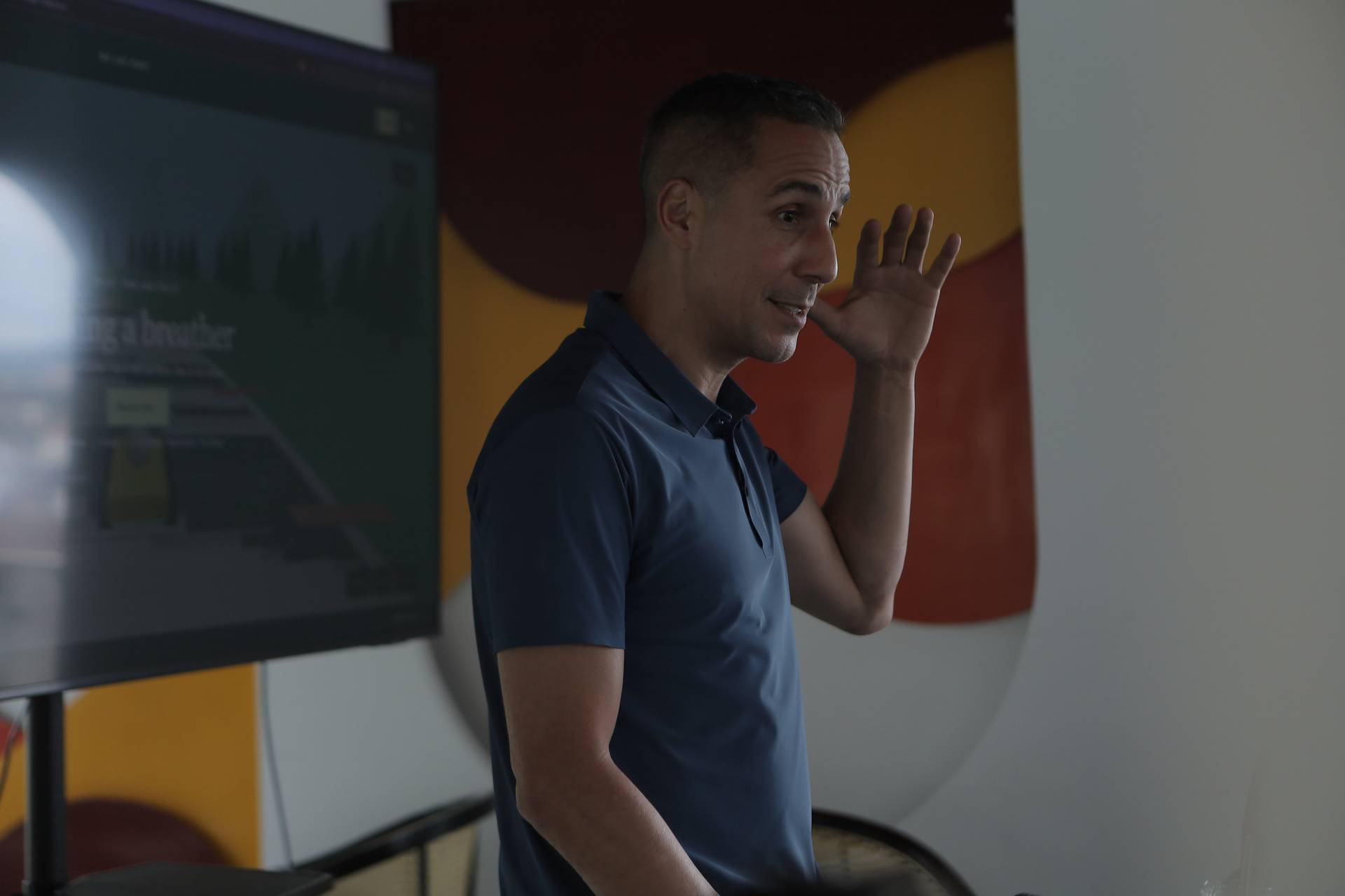 A man is giving a presentation in Đà Lạt, Vietnam, gesturing with his hand as he speaks to an audience.
