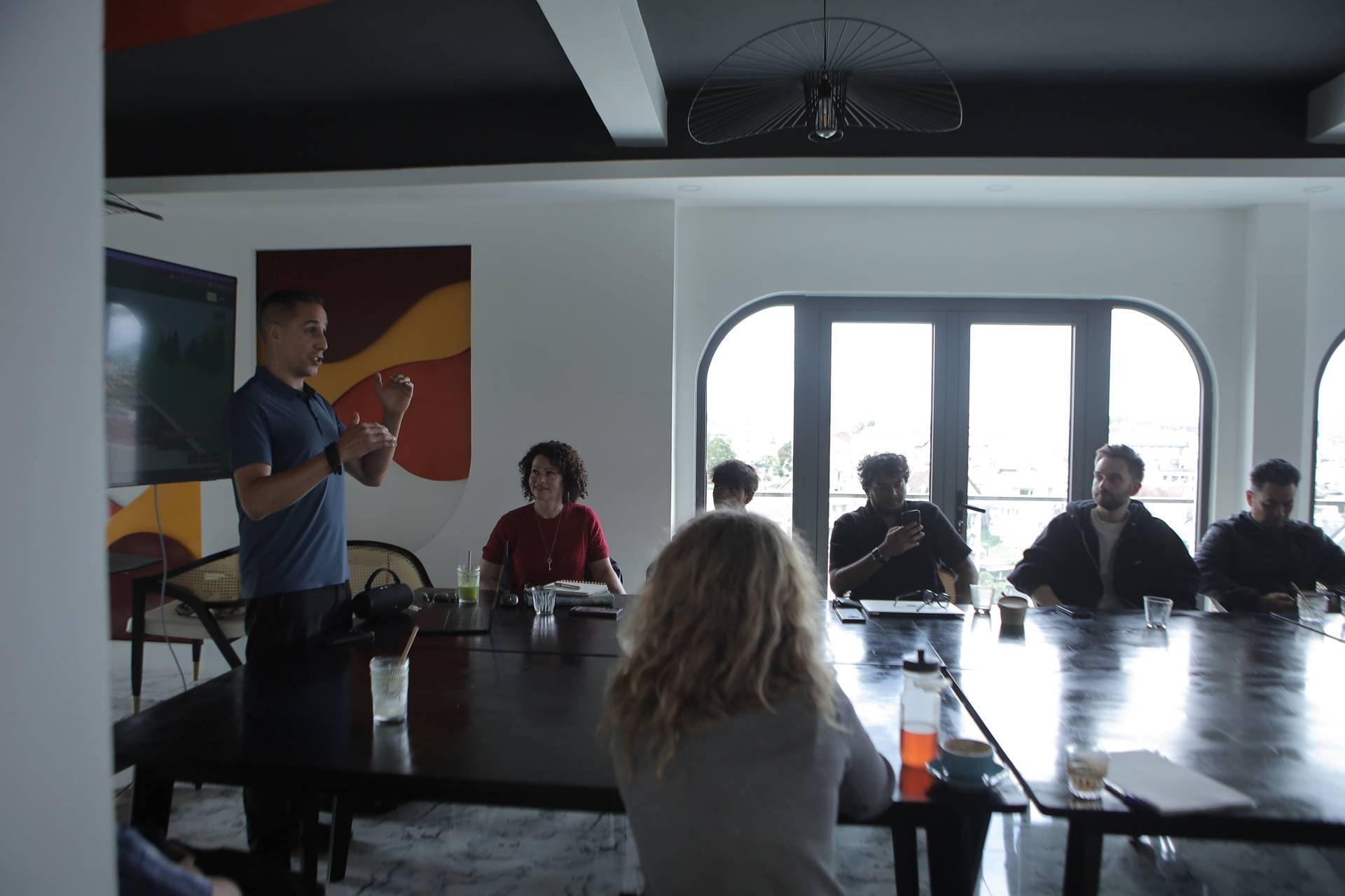 A professional meeting is taking place in a modern conference room with large windows overlooking Đà Lạt's scenic landscape.