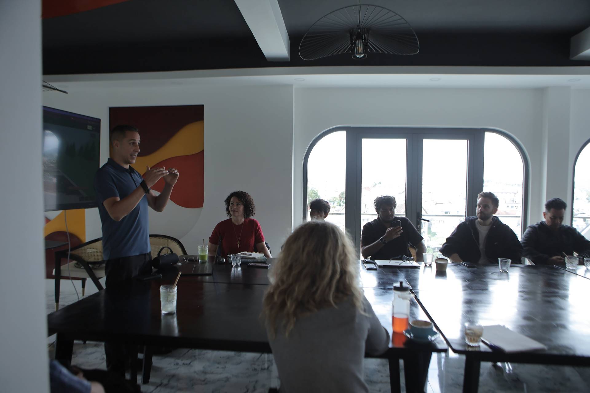 A professional meeting is taking place in a modern conference room with large windows overlooking Đà Lạt's scenic landscape.