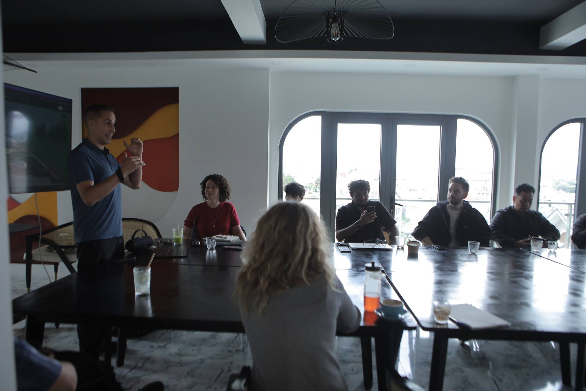 A group of professionals is engaged in a meeting around a large table in a modern conference room with panoramic windows overlooking Đà Lạt's scenic landscape.