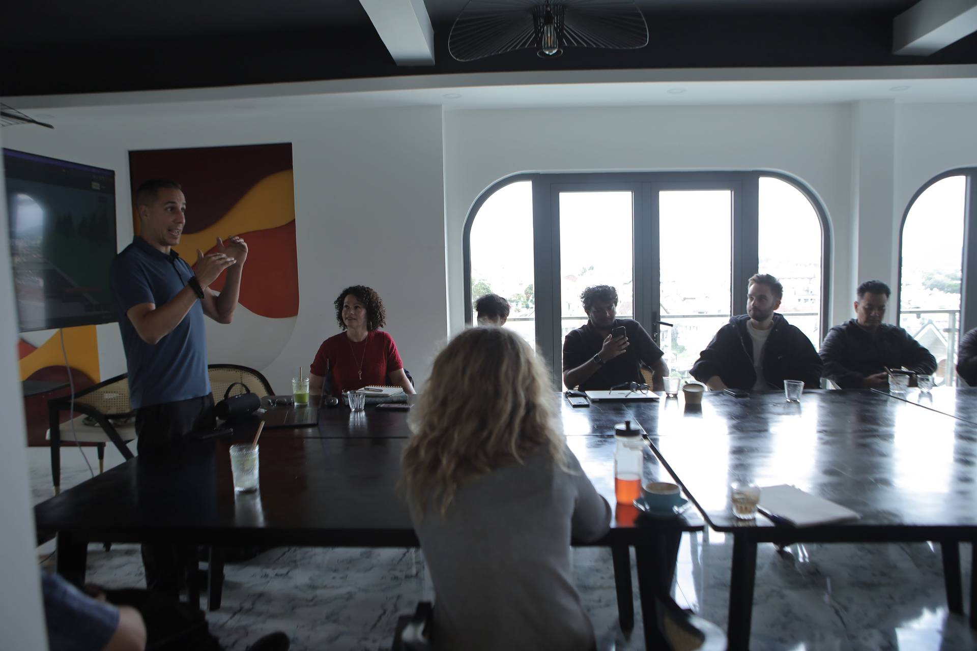 A group of professionals is engaged in a meeting around a large table in a modern conference room with large windows overlooking Đà Lạt's scenic landscape.