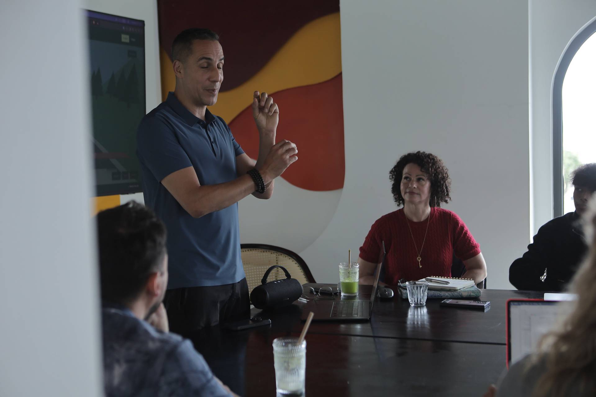 A man is giving a presentation to a small group of people in a modern office setting with vibrant artwork in Đà Lạt, Vietnam.