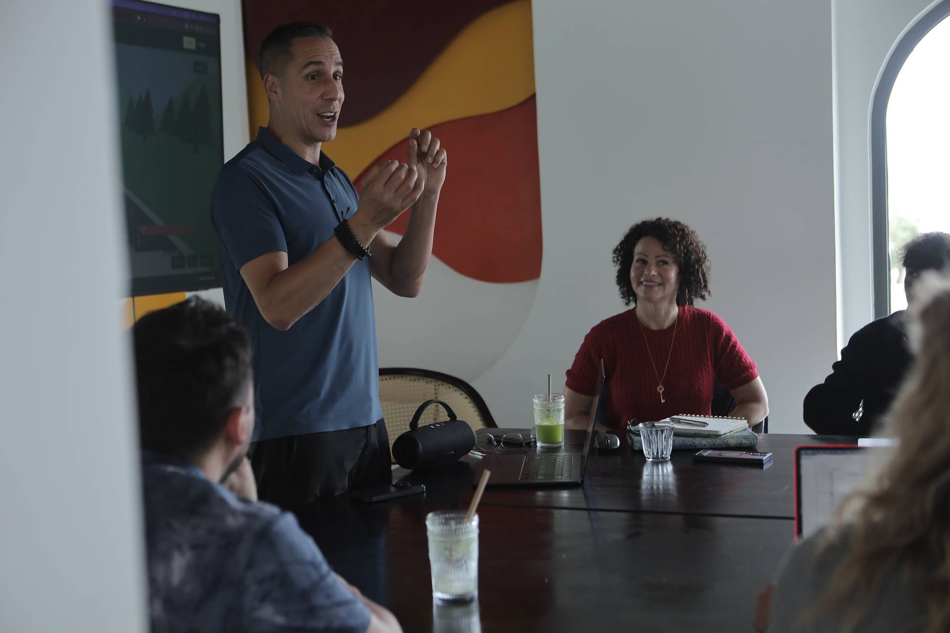 A man is giving a presentation in a modern conference room with a colorful mural in Đà Lạt, Vietnam.