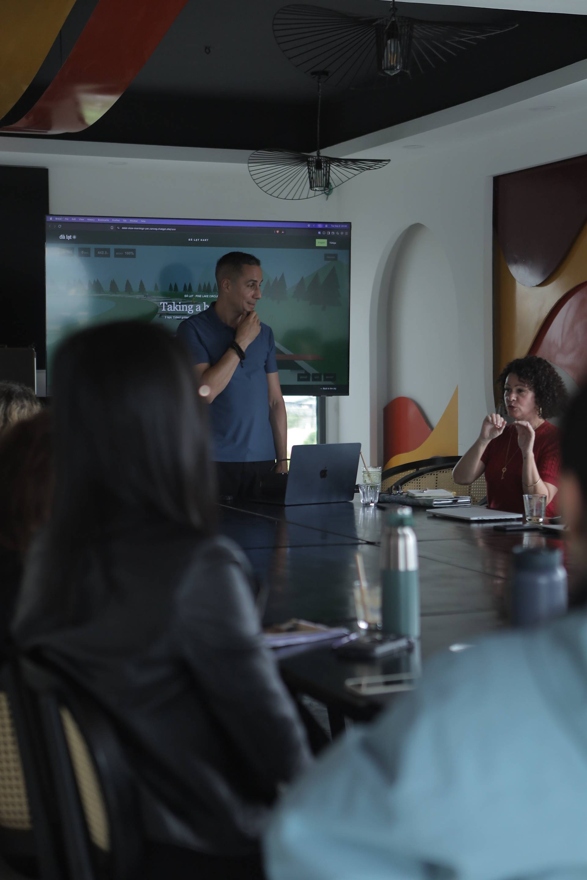 A professional meeting in Đà Lạt, Vietnam, featuring a presentation with a scenic backdrop displayed on a large screen.