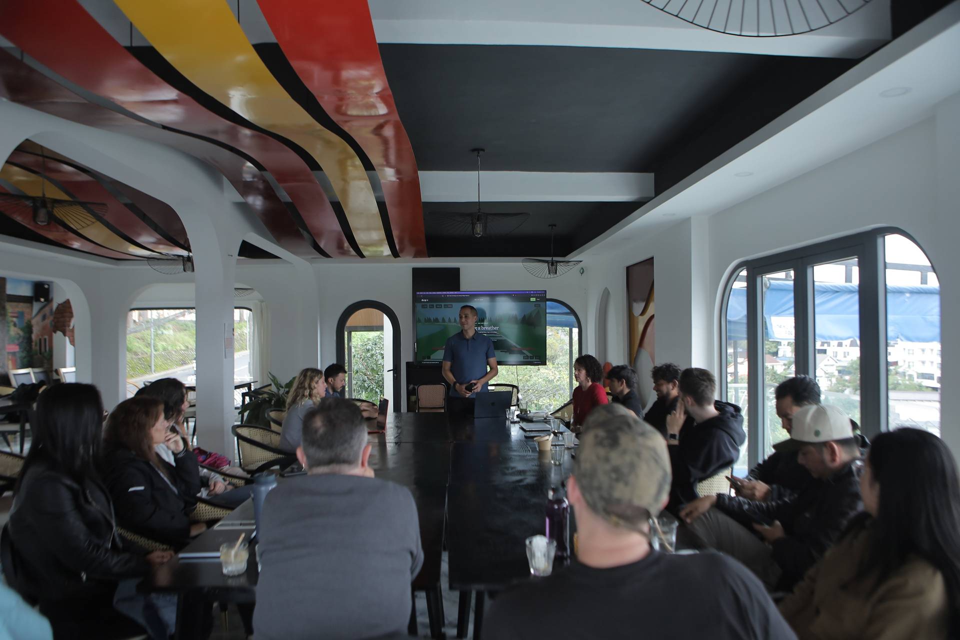 A professional meeting is taking place in a modern conference room with large windows overlooking Đà Lạt's scenic landscape.