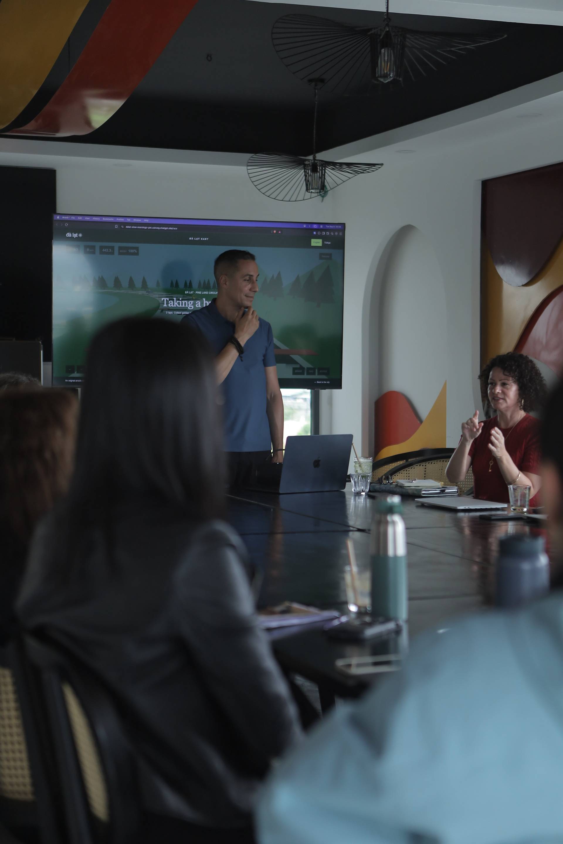A professional presentation in a modern conference room with attendees engaged in discussion about scenic landscapes of Đà Lạt.