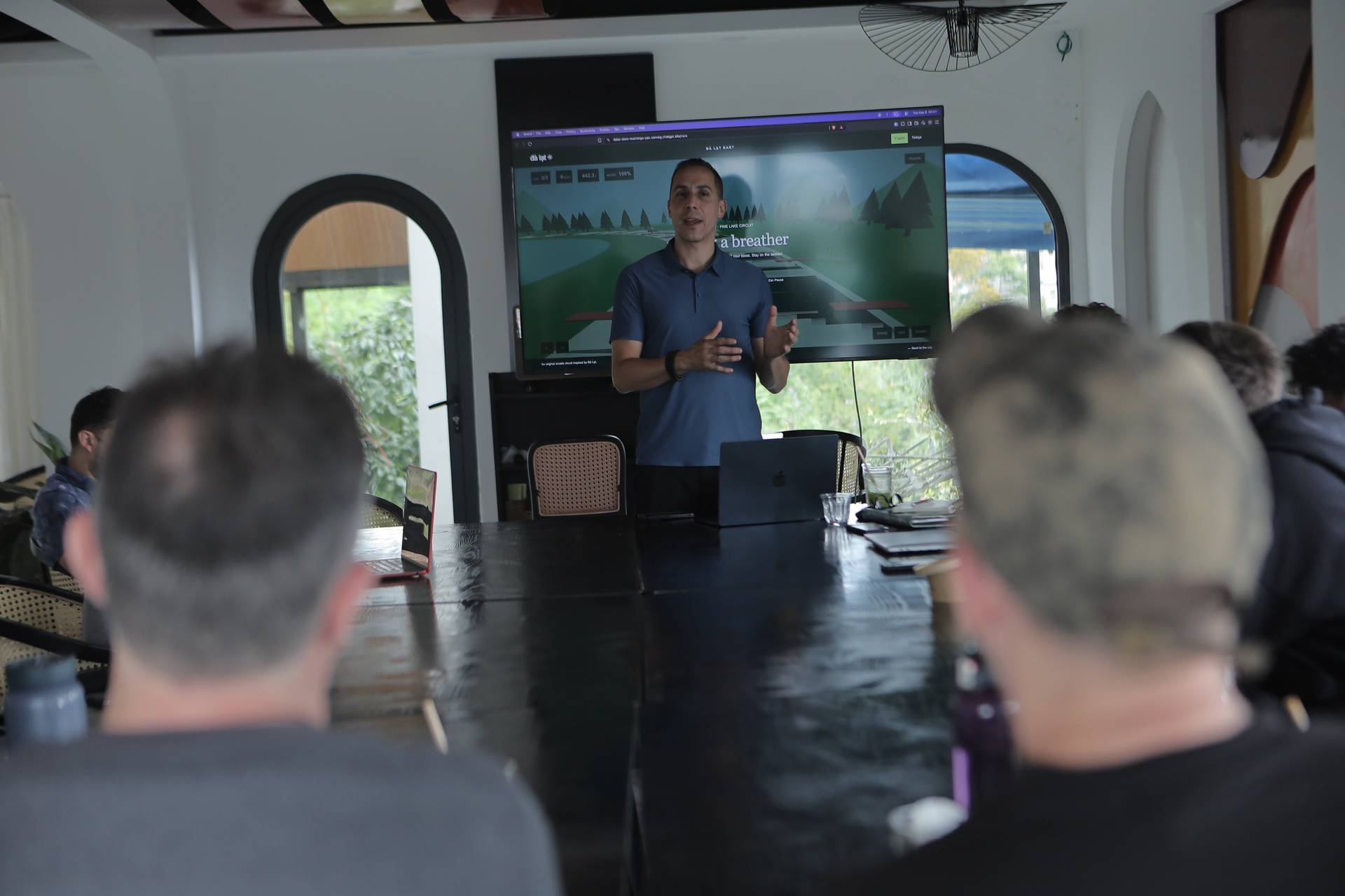 A professional presentation in a modern conference room in Đà Lạt, Vietnam, featuring a large screen displaying a scenic landscape and audience engagement.