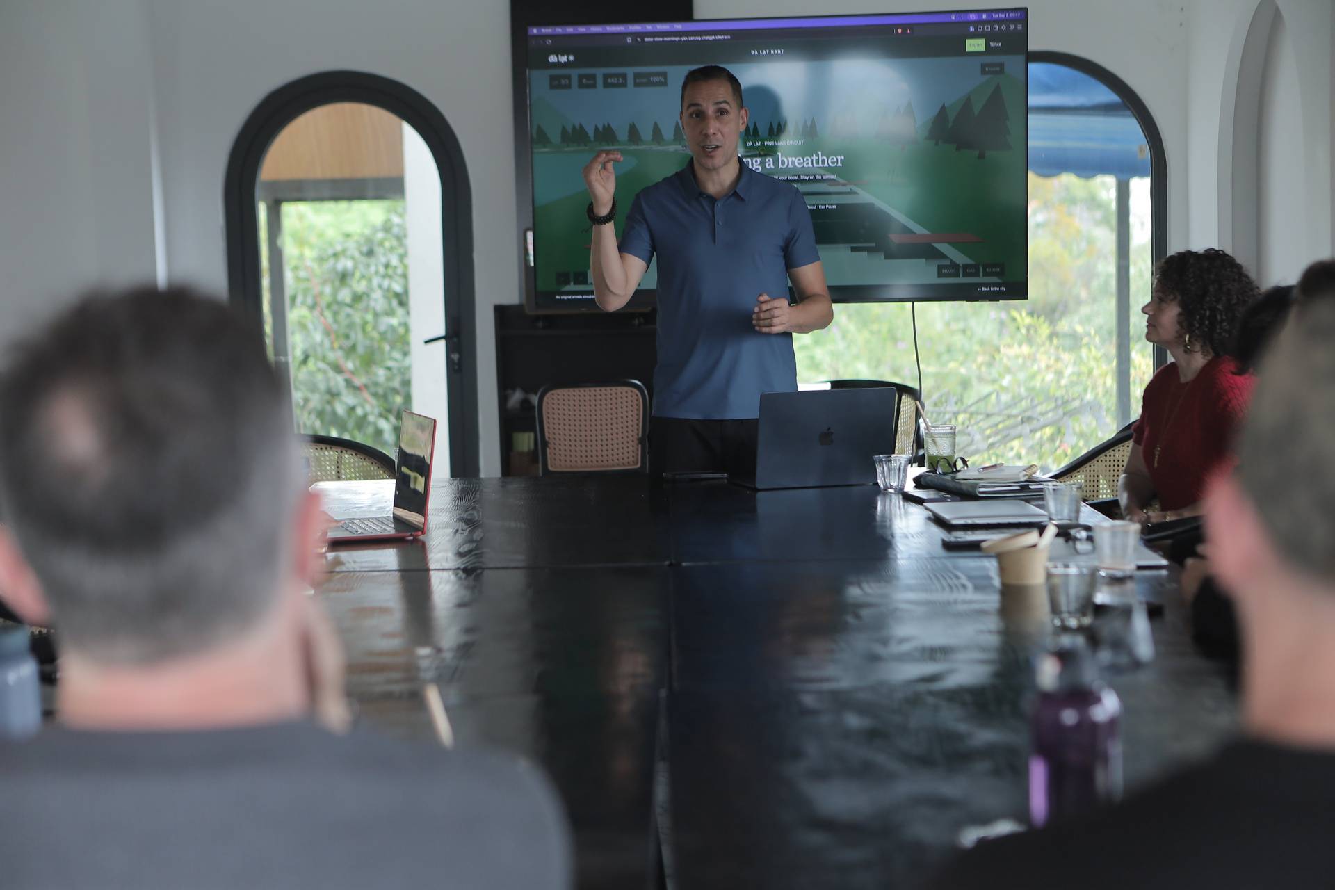 A professional presentation in a modern conference room with attendees focused on a speaker discussing a scenic route in Đà Lạt, Vietnam.