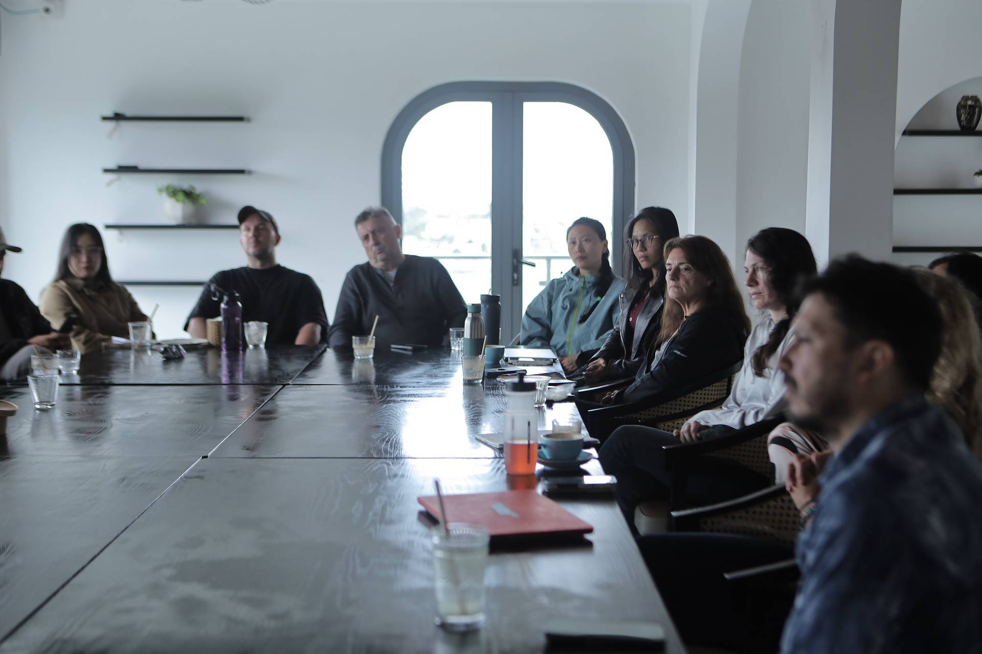 A group of professionals is seated around a long table in a modern conference room in Đà Lạt, Vietnam, engaged in what appears to be a serious meeting or discussion.