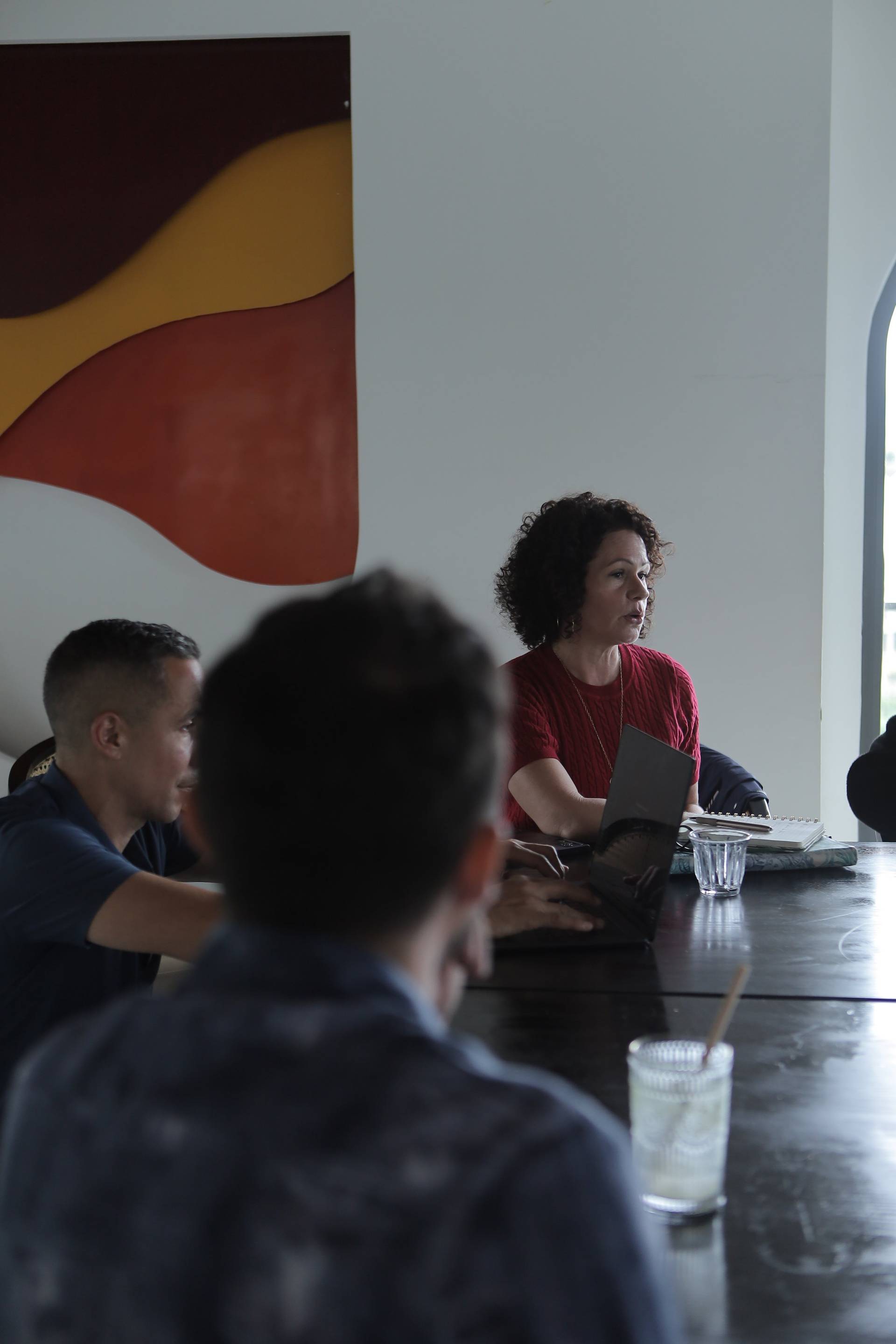 A group of individuals engaged in a meeting or discussion around a table in a modern setting with vibrant wall art in Đà Lạt, Vietnam.