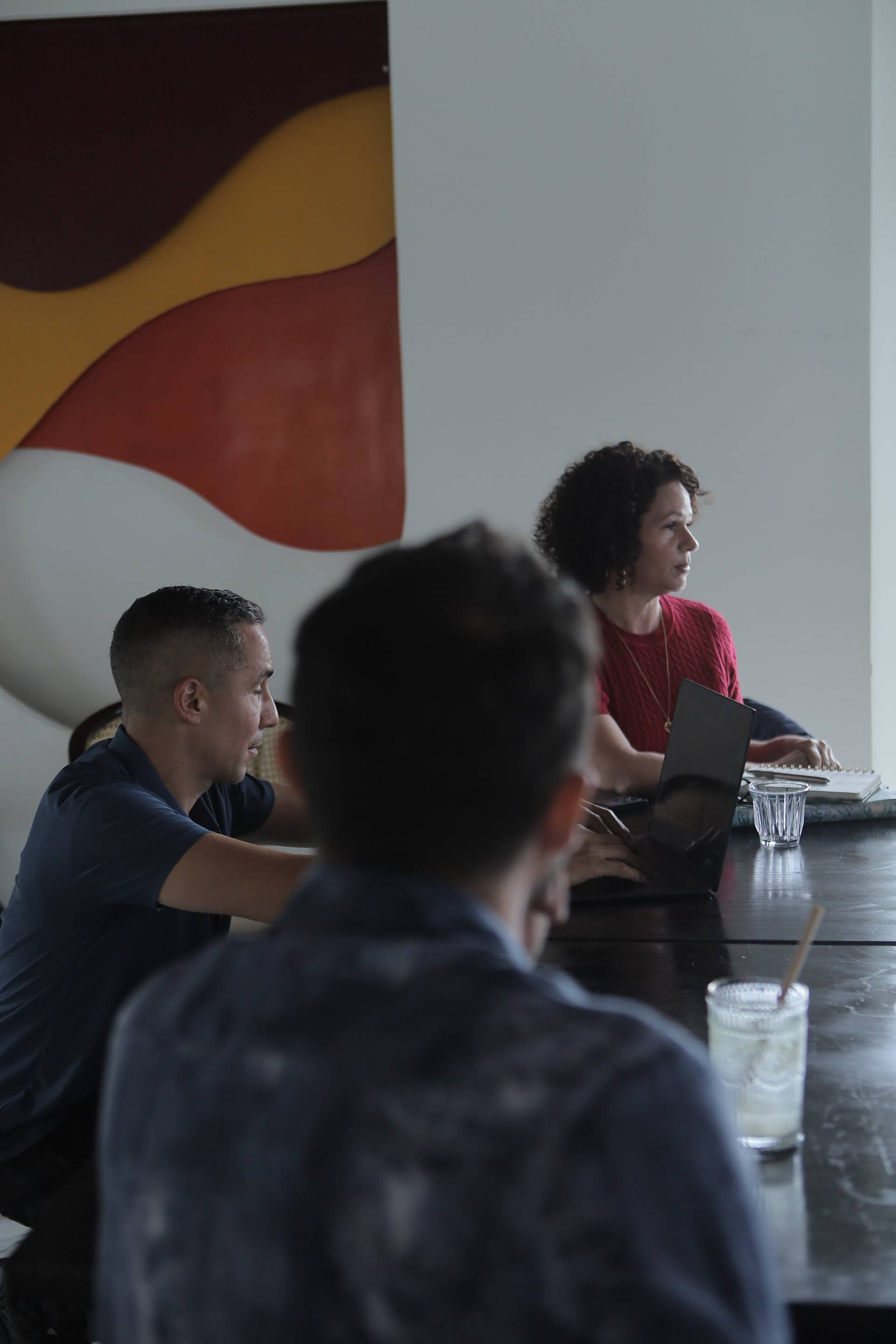 A group of individuals engaged in a meeting or discussion around a table with modern decor and vibrant wall art in Đà Lạt, Vietnam.