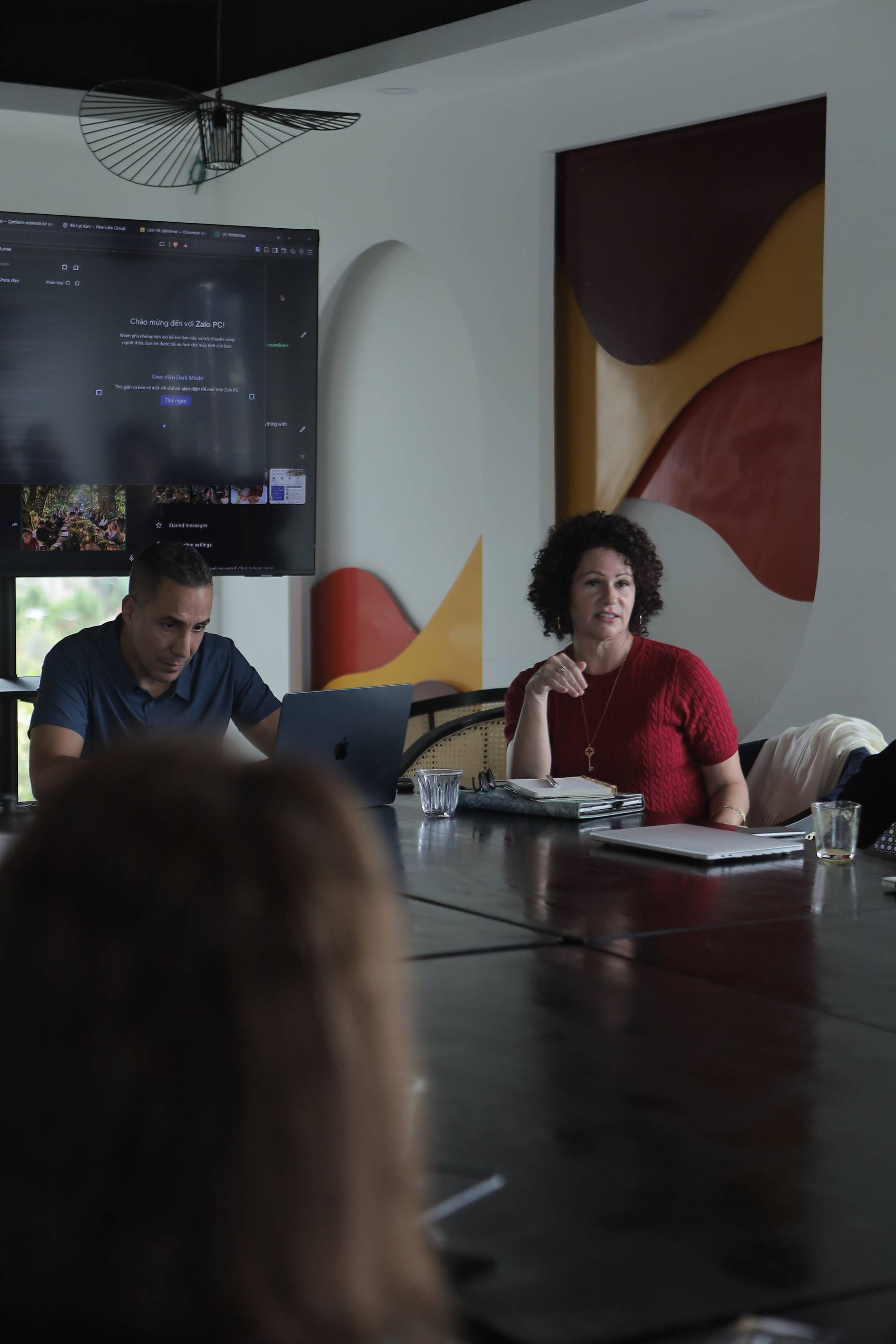 A professional meeting in a modern office space with attendees engaged in discussion around a conference table.