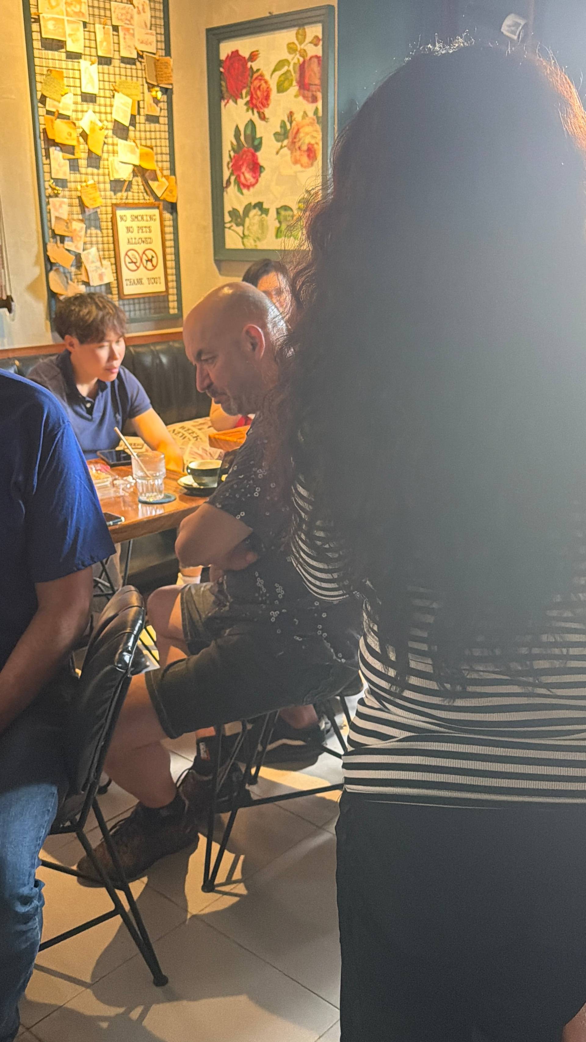 A cozy café in Đà Lạt with patrons enjoying drinks and conversation over a meal, surrounded by local decor and warm lighting.