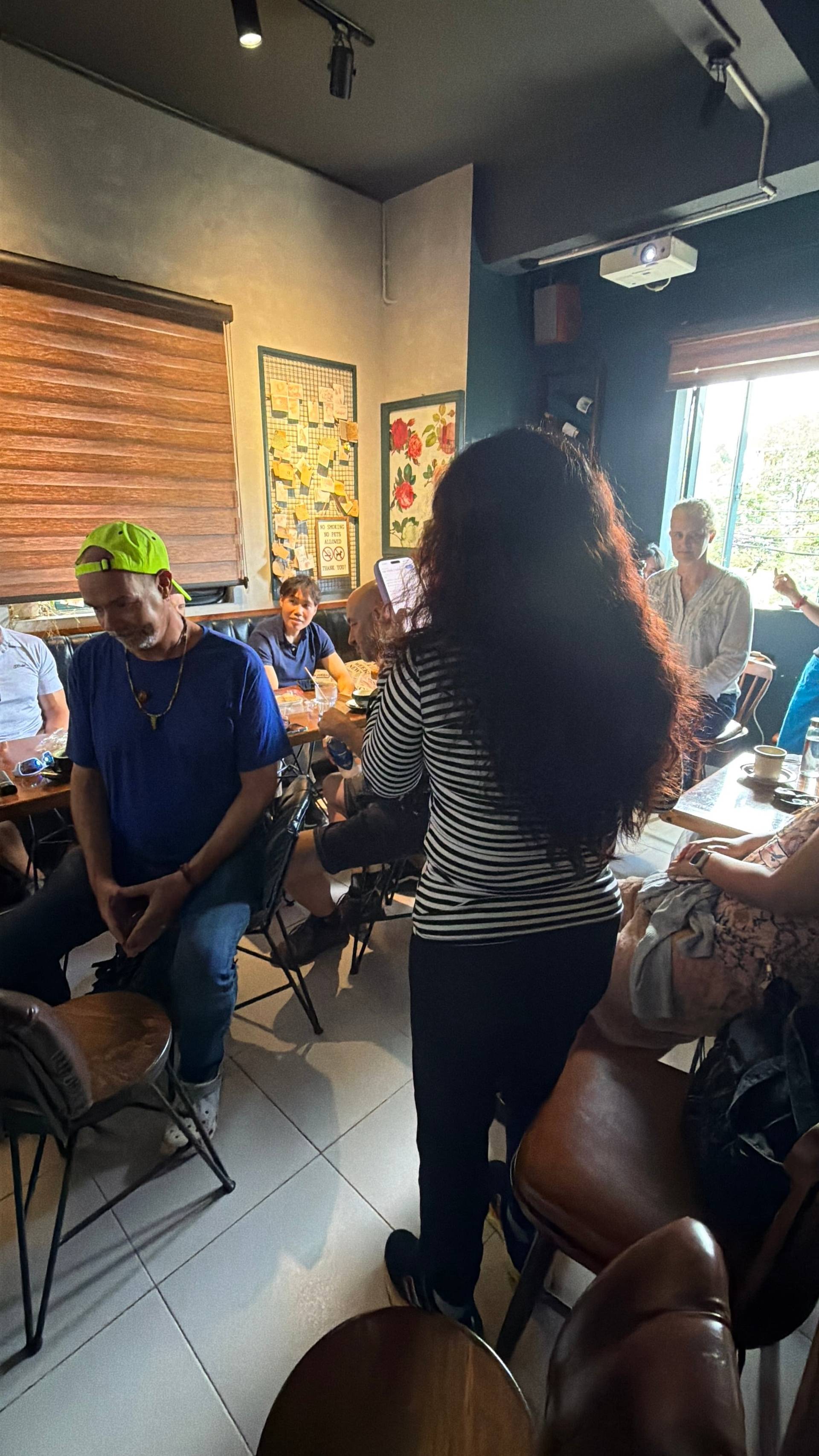 A lively gathering of friends in a cozy café in Đà Lạt, Vietnam, with people engaged in conversation and enjoying drinks.