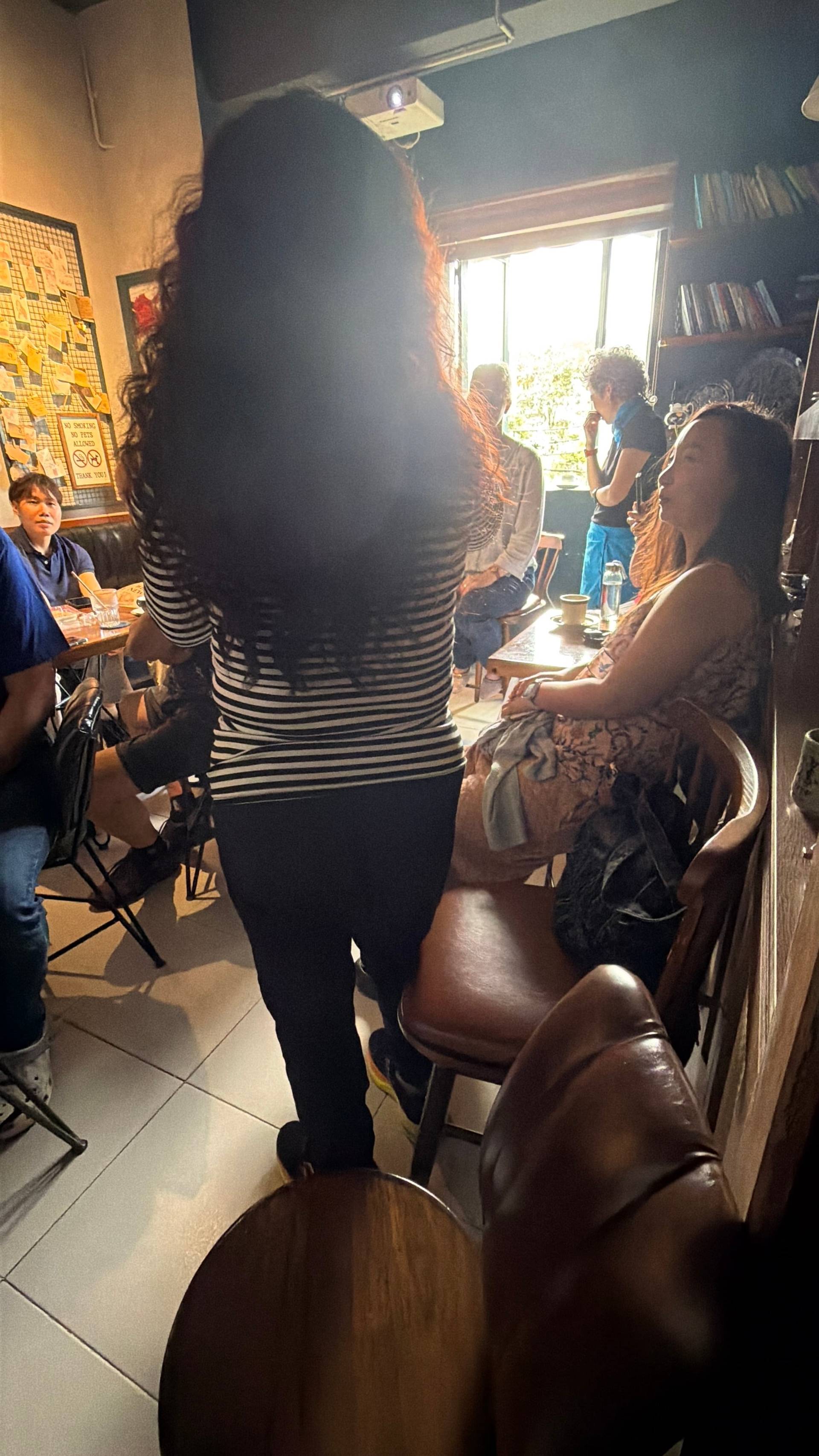 A lively gathering in a cozy café in Đà Lạt, Vietnam, with friends enjoying board games and casual conversations under warm lighting.