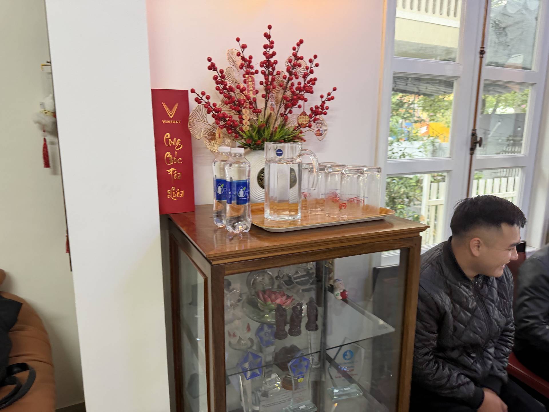 An elegant display shelf featuring a striking red berry floral arrangement, branded signage, and curated beverage glasses in a high-end Vietnamese hospitality setting. The refined presentation reflects Đà Lạt's reputation for upscale dining and entertainment experiences.