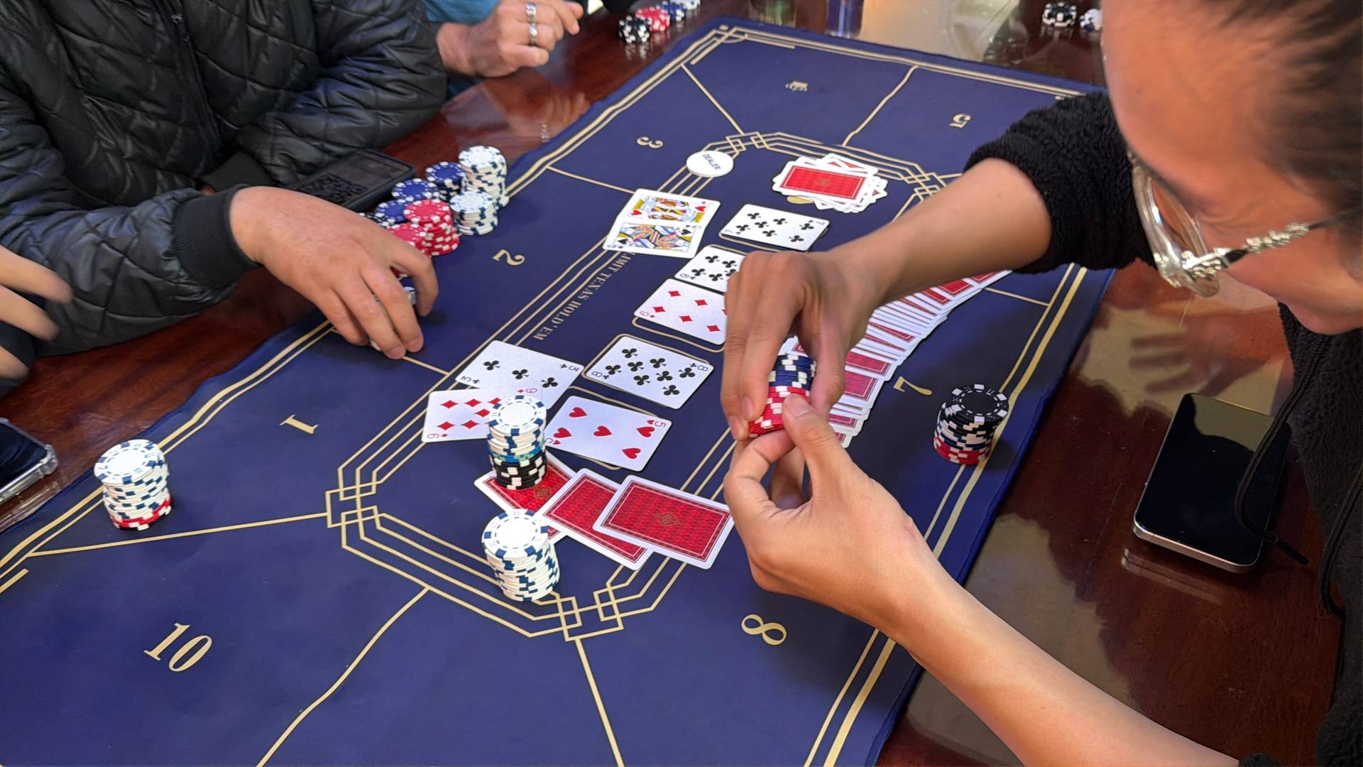 An intense moment unfolds at a baccarat table during a gaming event in Đà Lạt, with players' hands managing cards and chips in active play.
