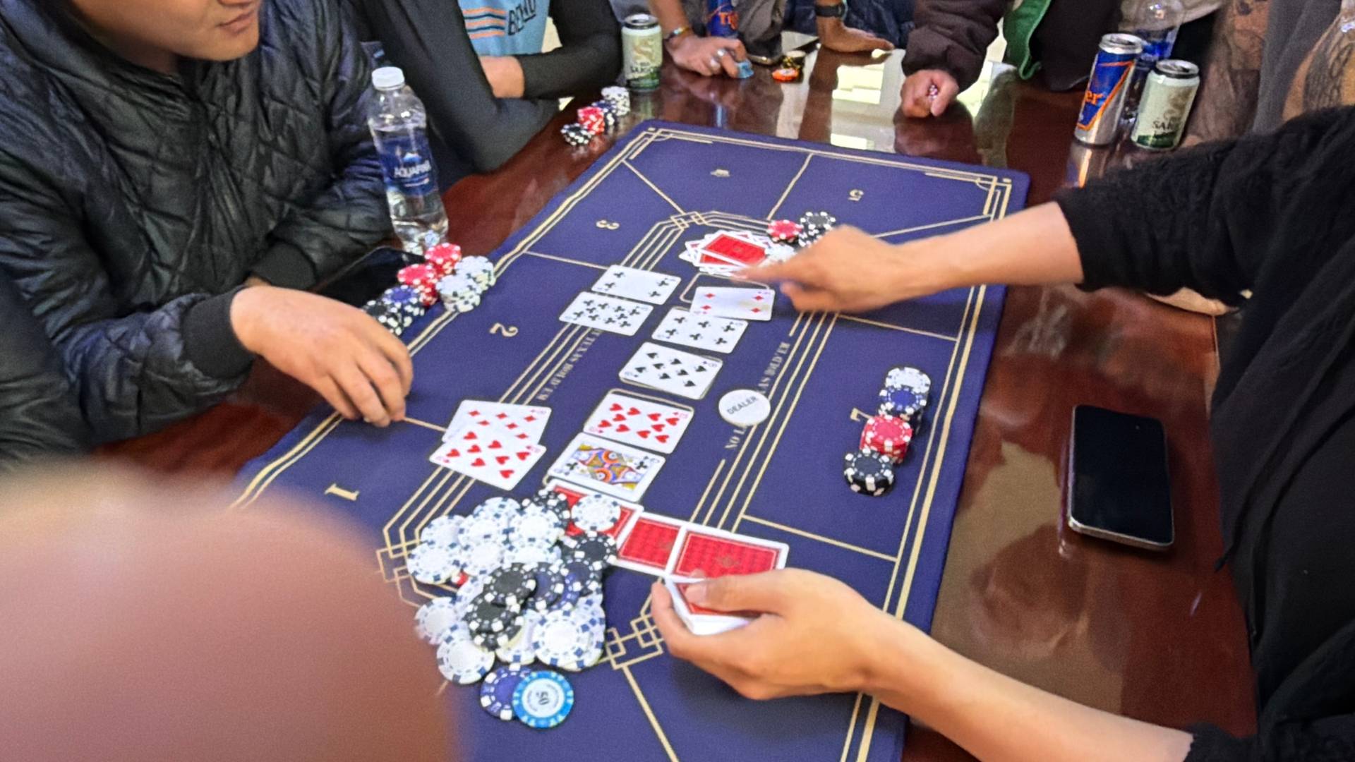 Players' hands actively engage in baccarat gameplay with cards and poker chips visible on a professional gaming table during a Đà Lạt event.