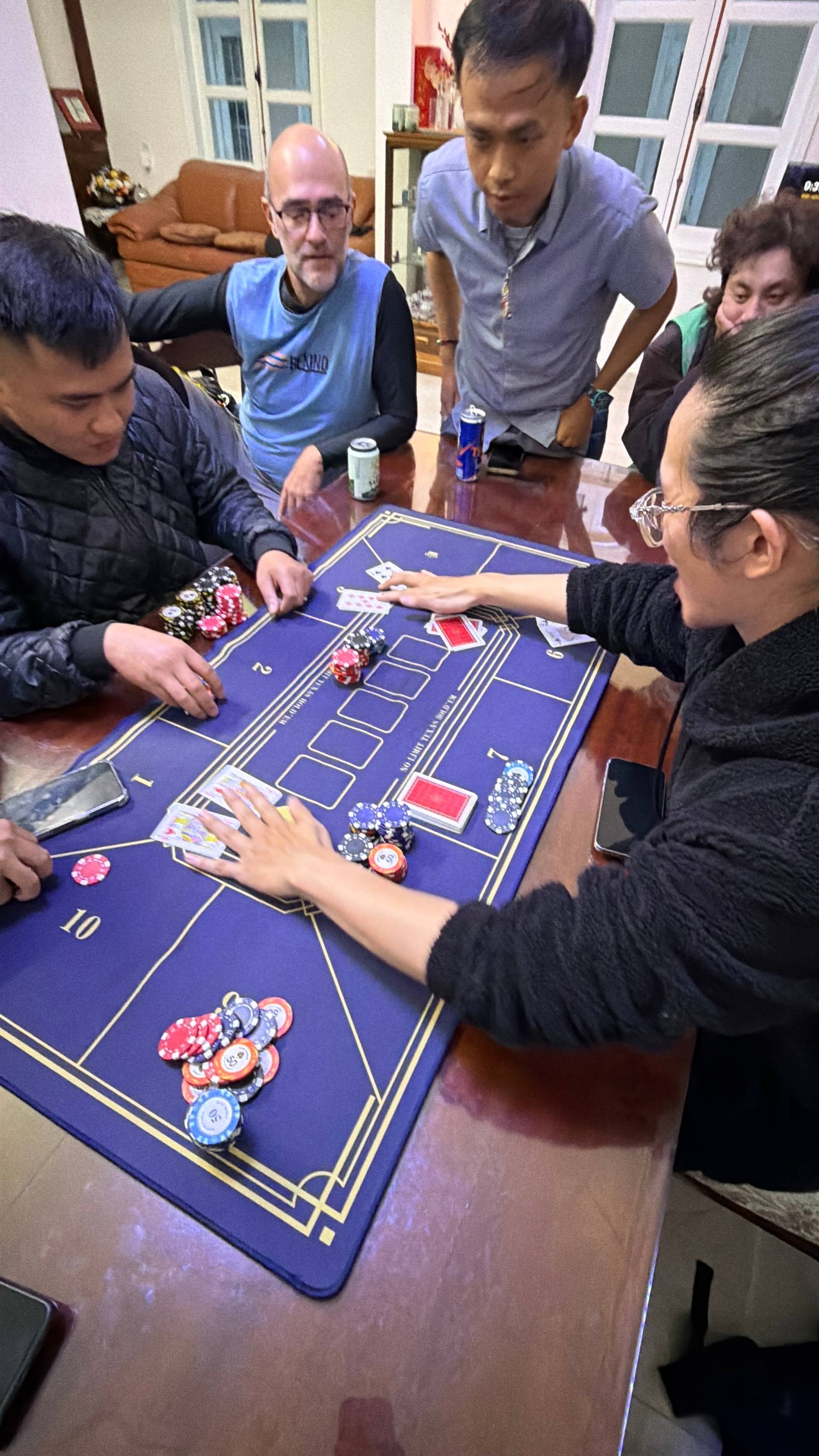 Multiple guests participate in a baccarat game at an elegant indoor venue in Đà Lạt, concentrating on gameplay with poker chips and cards on the professional table.